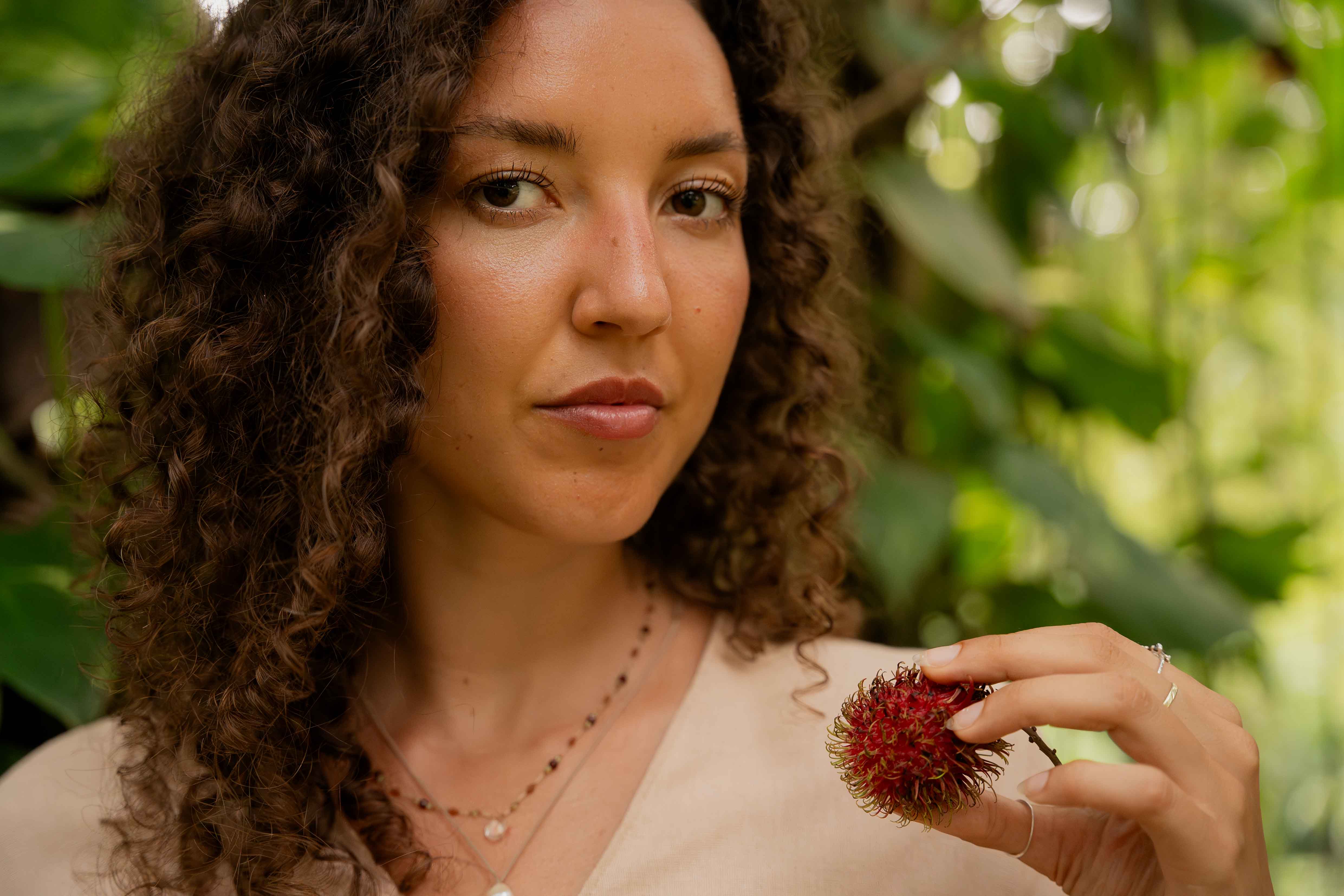 Girl looking into camera holding rambutan