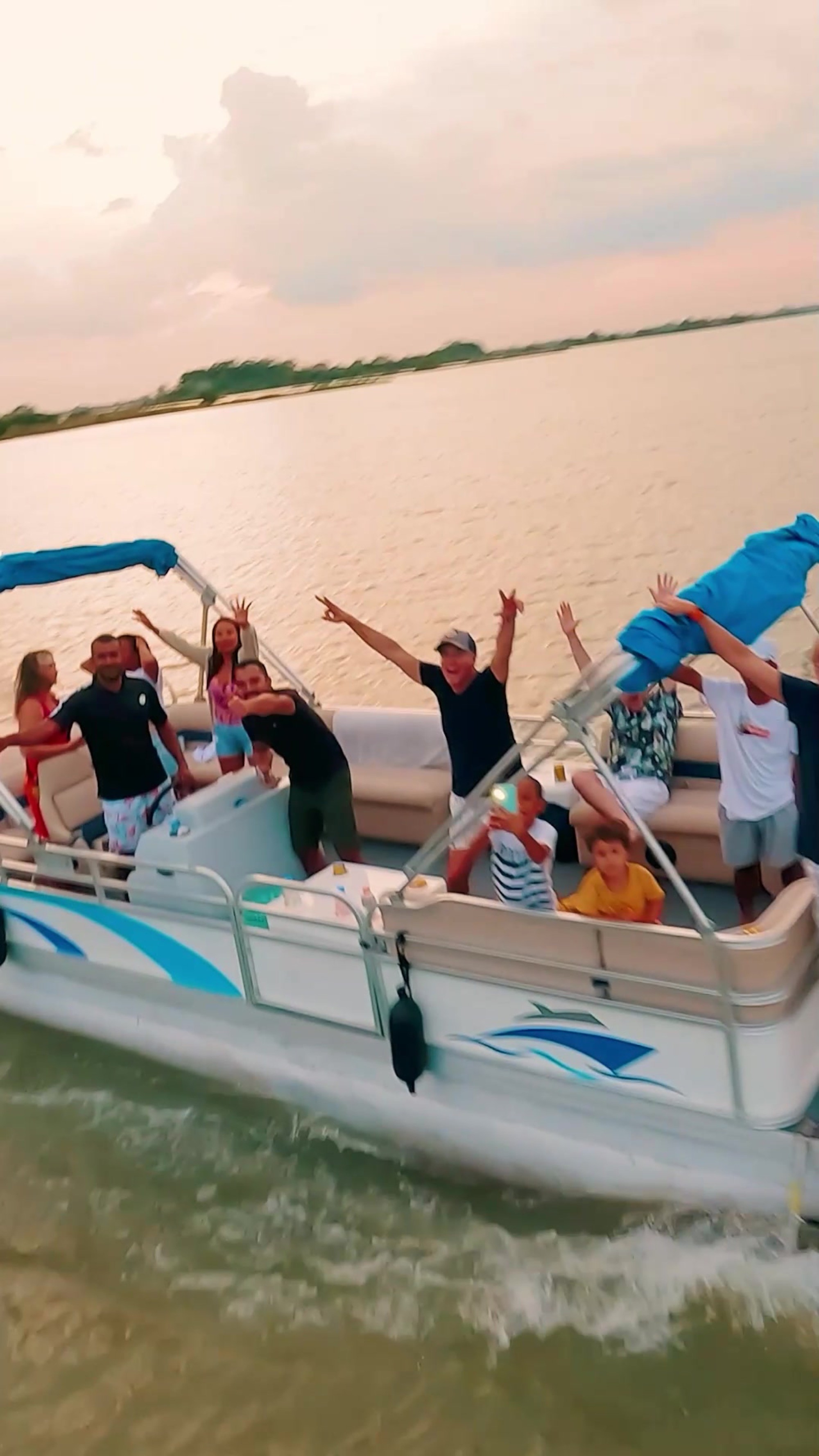 Grupo de personas celebrando con los brazos en alto a bordo de una lancha sobre el agua al atardecer