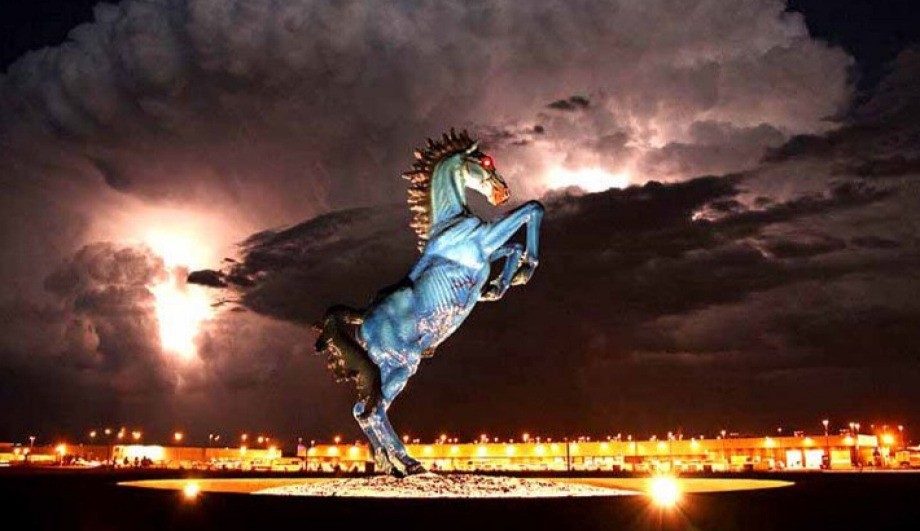 Blue Mustang sculpture with glowing red eyes at Denver International Airport against a dramatic lightning storm at night