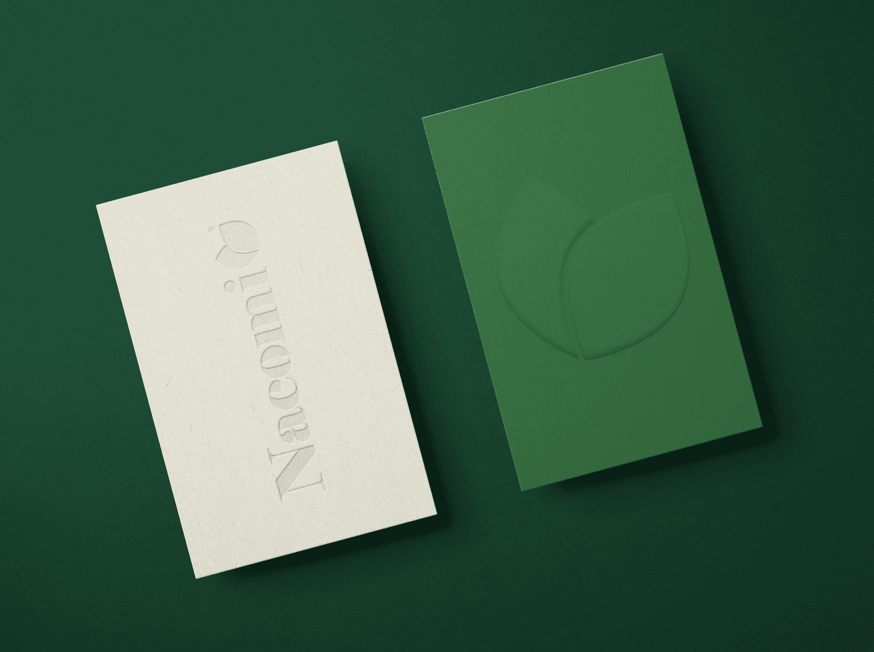 Two playing cards, one white and one dark green, are laid on a green surface.