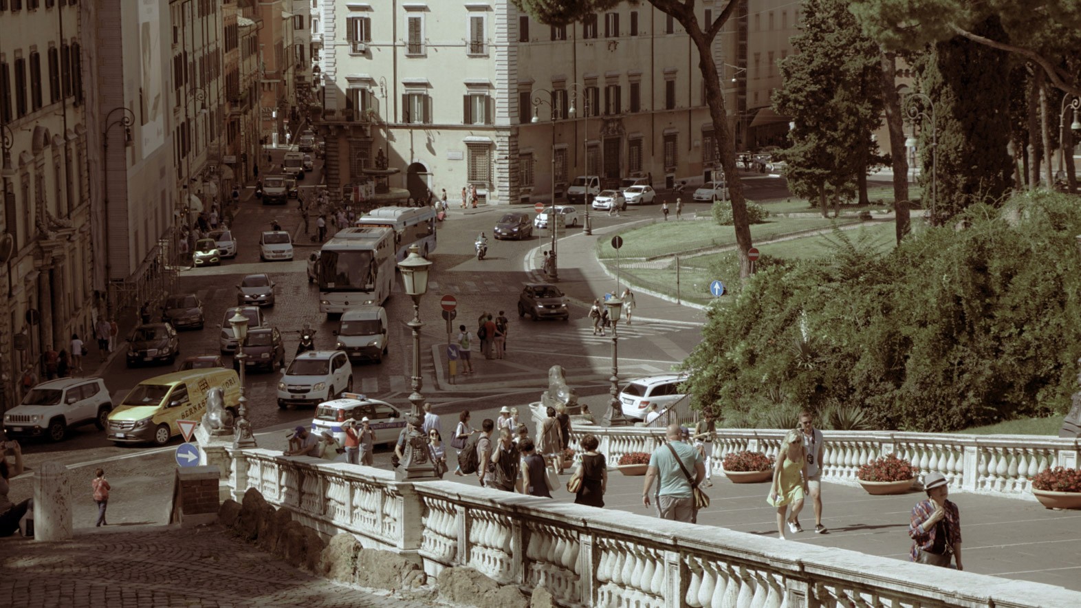 Busy Roman street with cars, buses, and pedestrians viewed from an elevated terrace, photographed by Janice Chen.