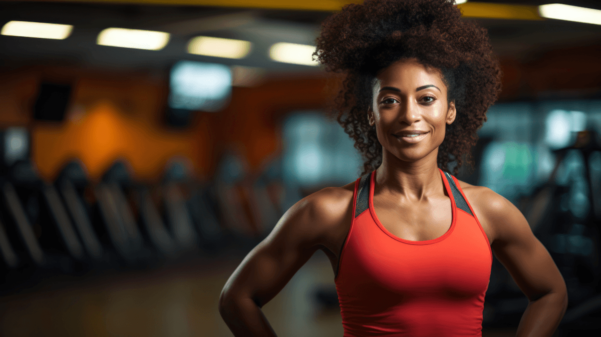 Confident Black woman with afro hair in red tank top posing in gym