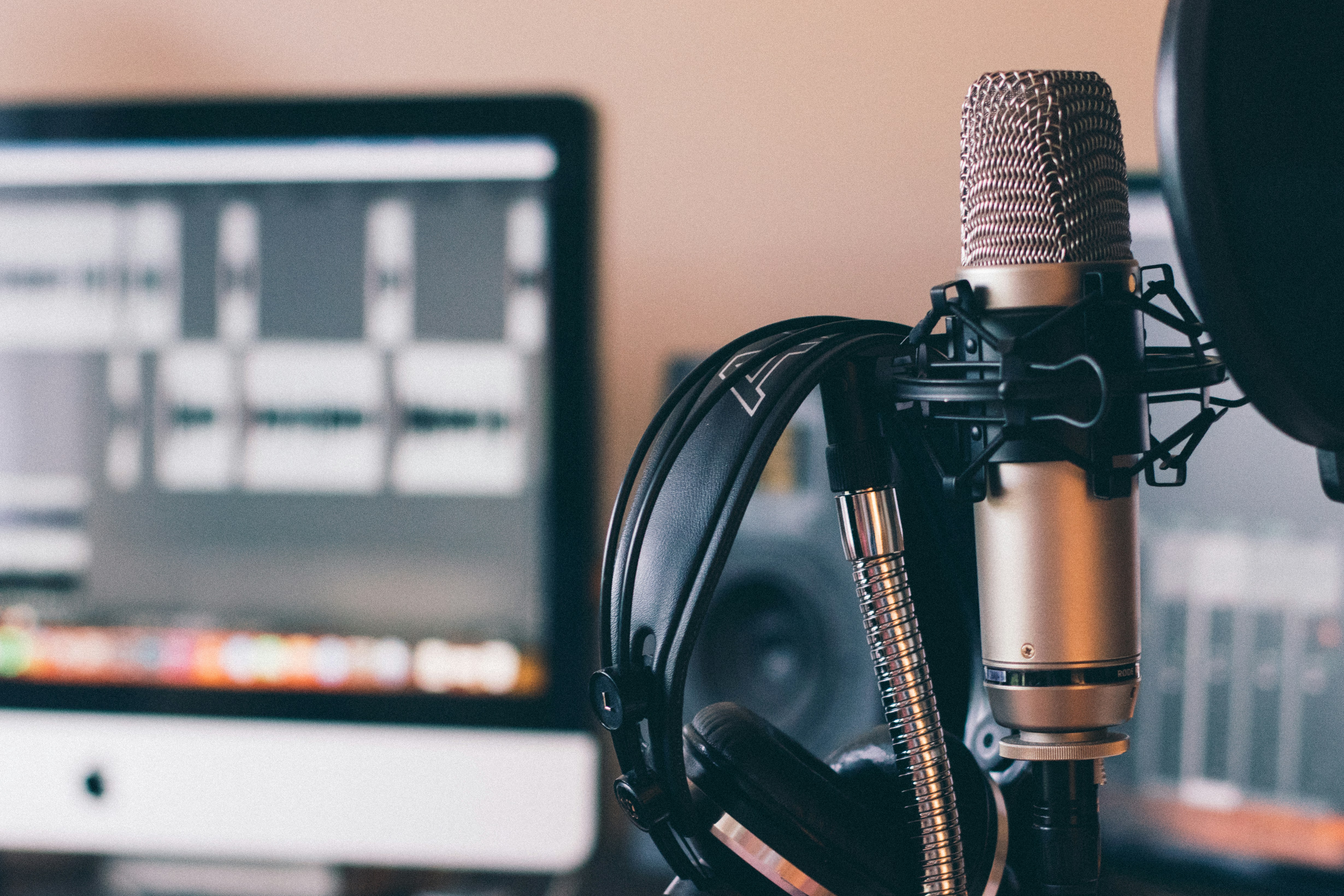 Microphone and headphoones in front of a computer monitor with a audio workstation open