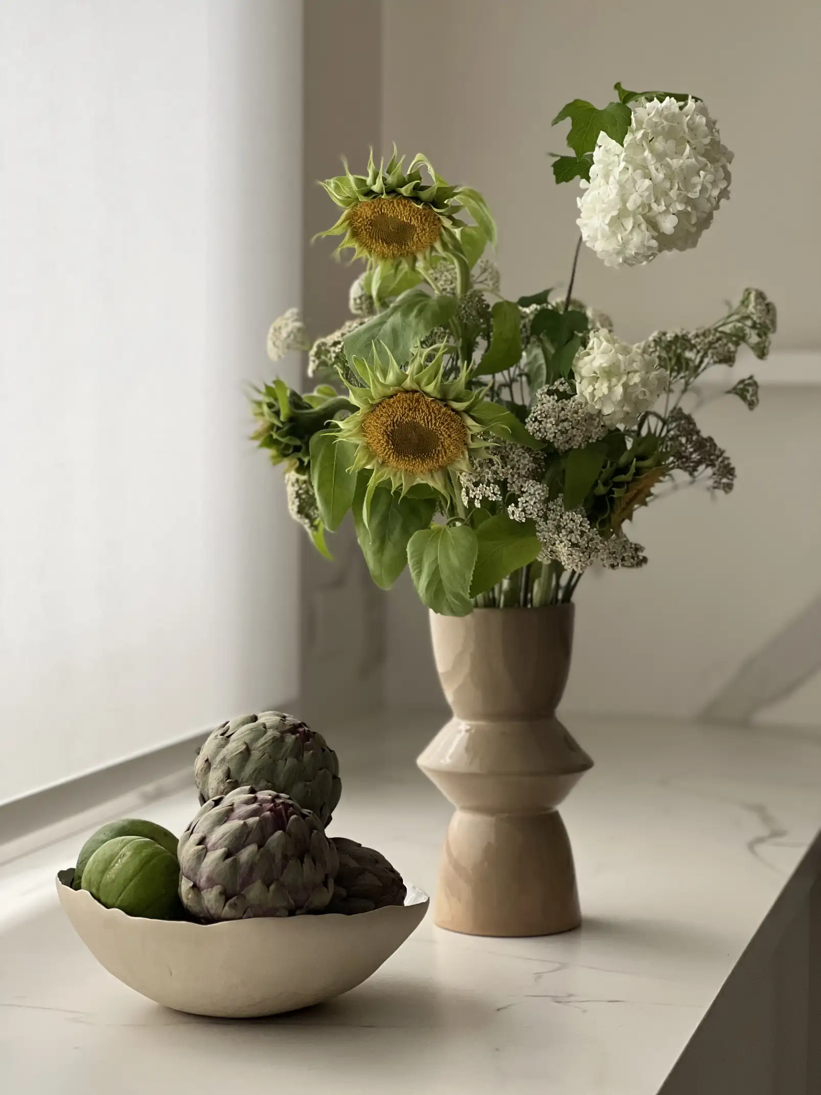 Composición con girasoles y alcauciles en cerámica para interioristas que buscan transmitir calidez natural y estética orgánica.