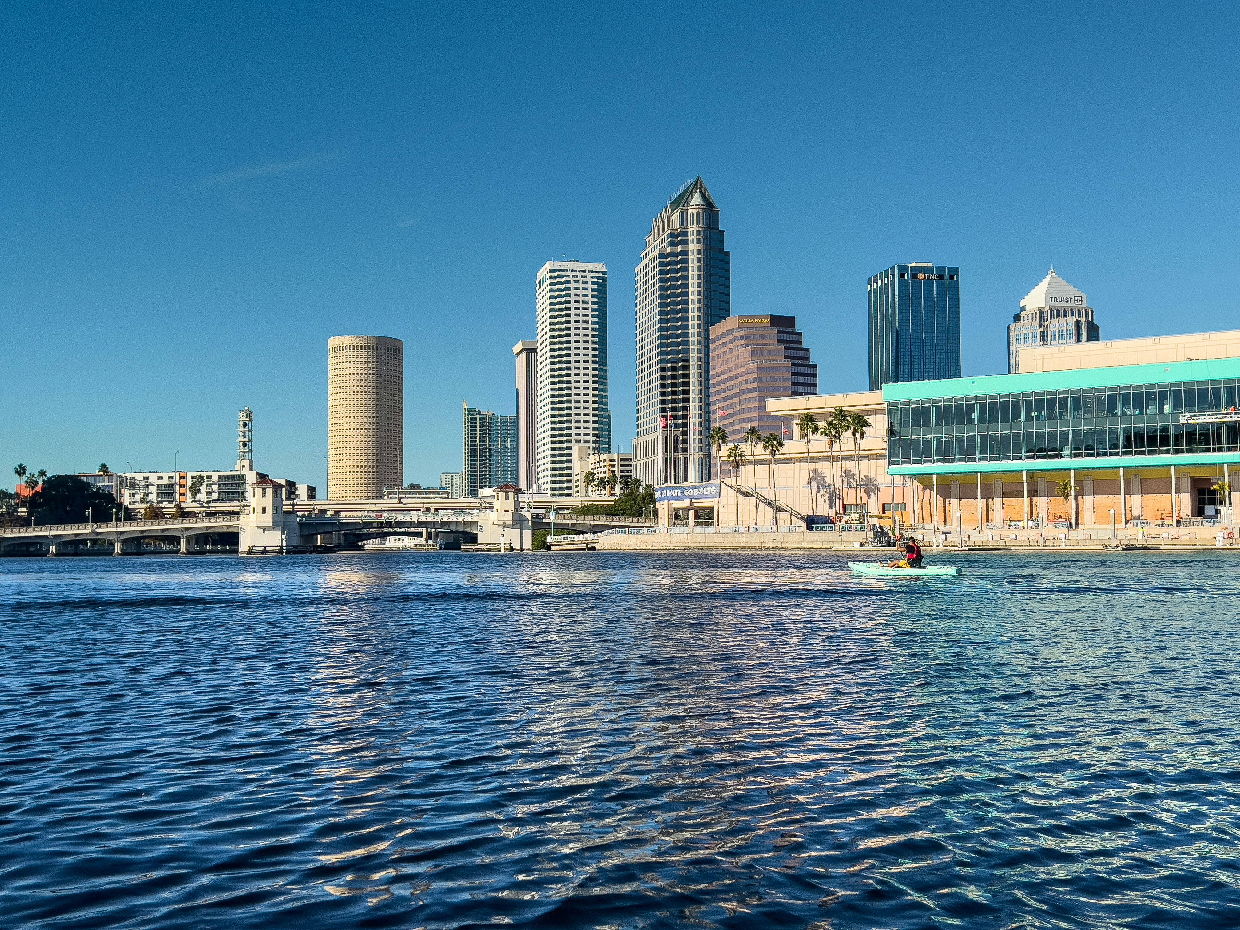 a man in a boat on a river in front of a city