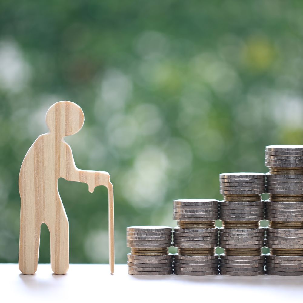 Altersvorsorge mit Holzfigur und Geldmünzen