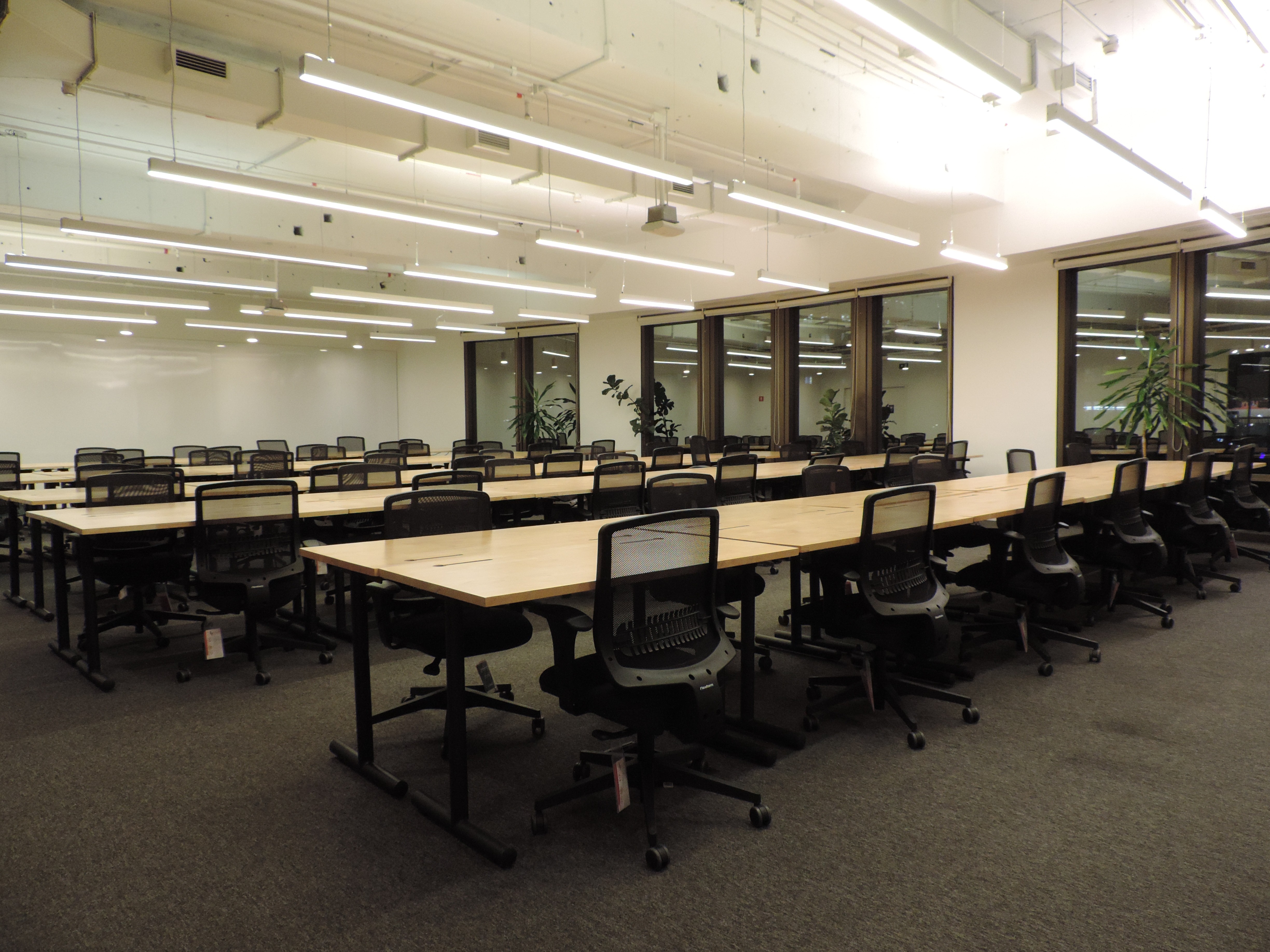 Beige interior with natural stone walls, sunlight, and geometric shadows over a calm water pool.