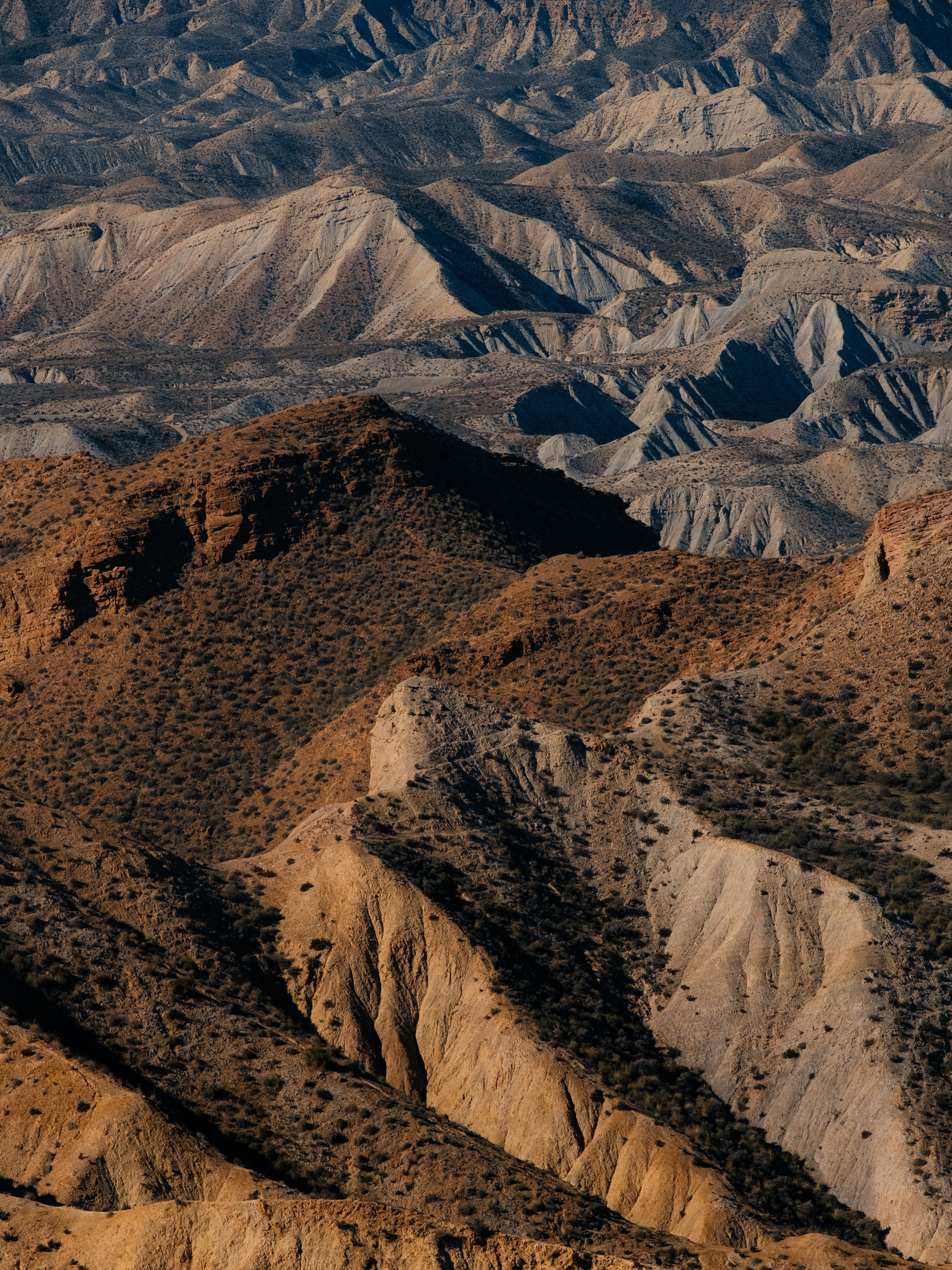Arid desert landscape with rolling hills and shadows.
