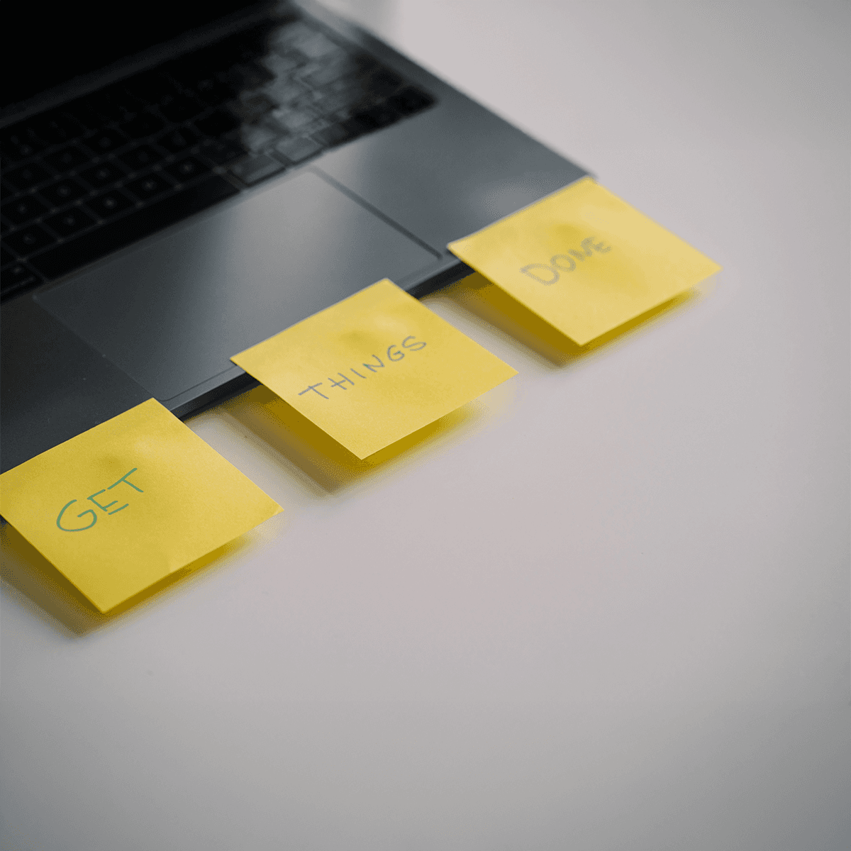 picture of a laptop with three post-it notes attached to it with the text "get", "things", "done" on them