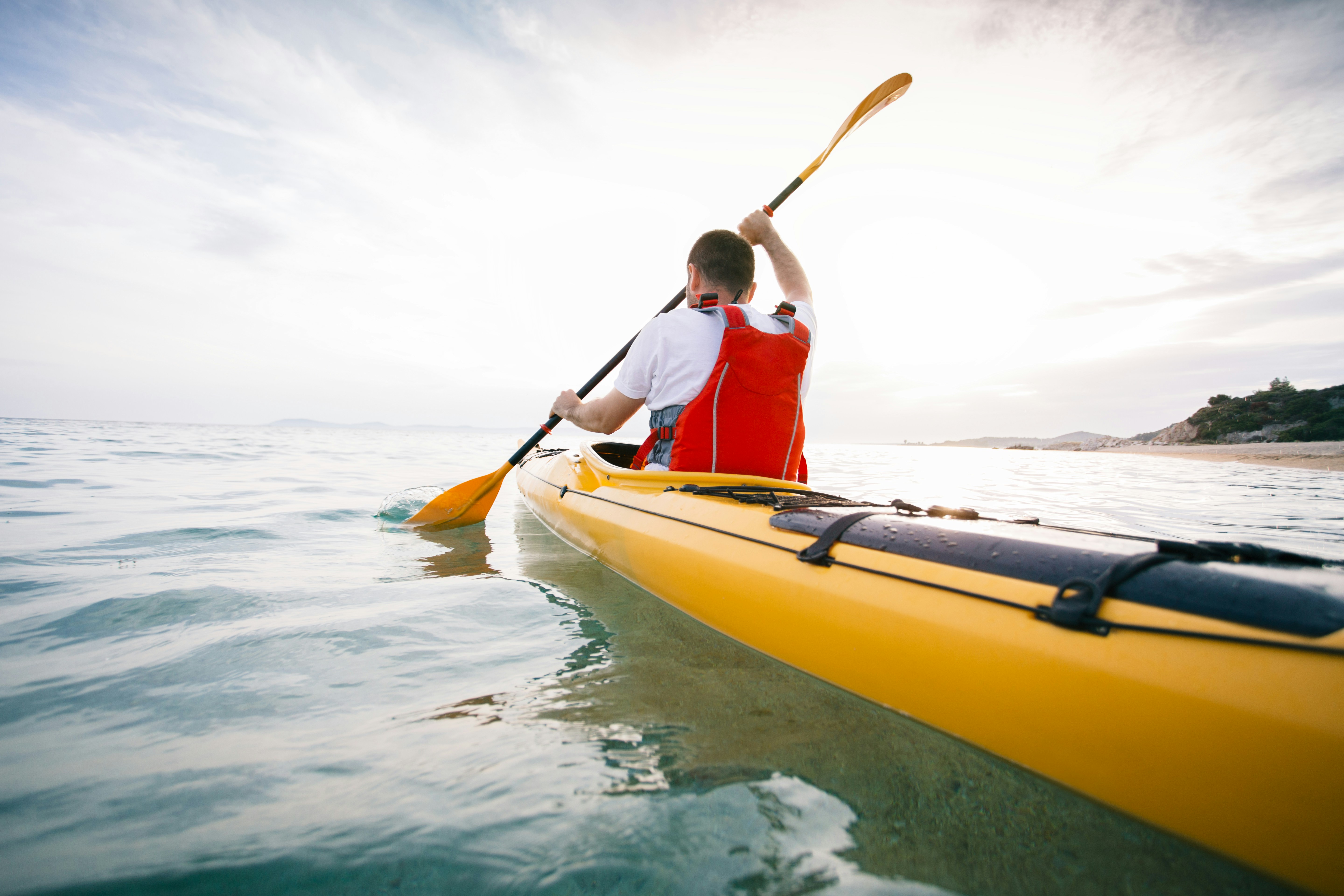 Man kayaking inland while wearing a life vest.