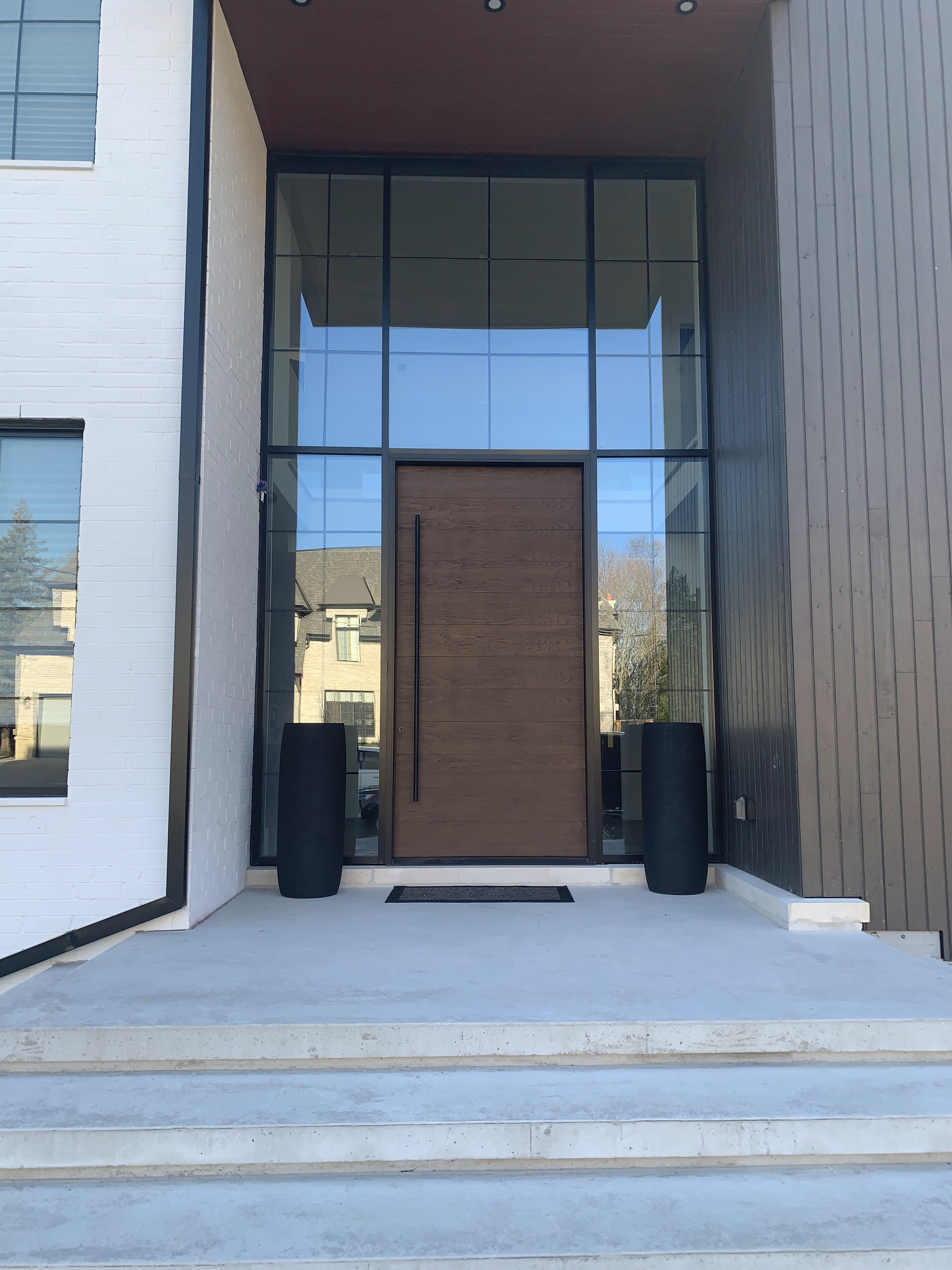 A bright, welcoming foyer seen through an open custom-built wood-clad entry door.