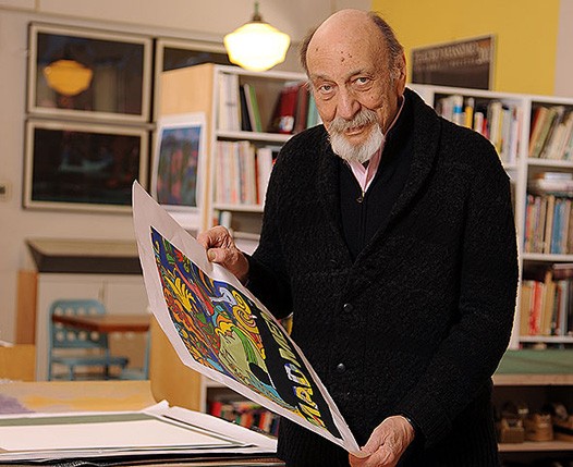 A photo of an old man holding a sample of a cartoon poster.