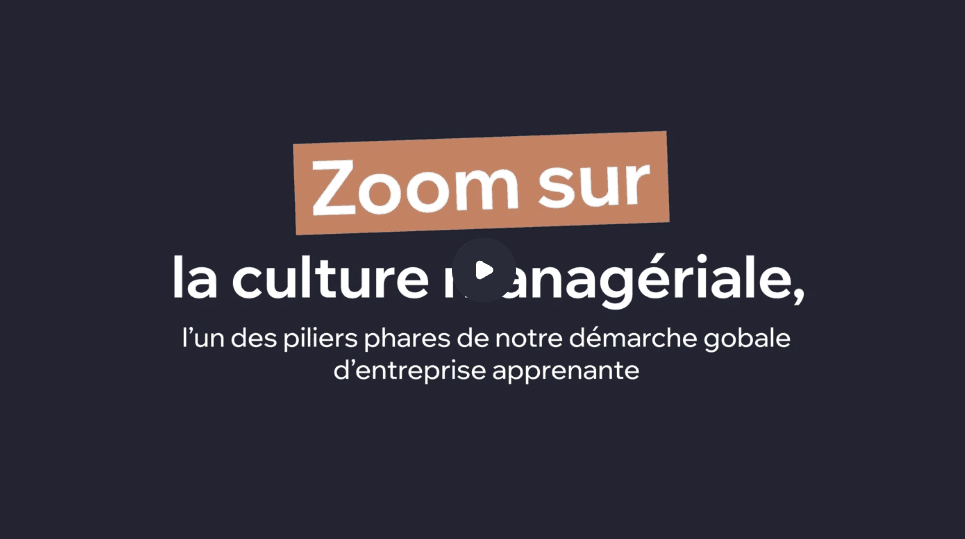 A person in a red coat with earmuffs and large sunglasses smiles while lying on snow, arms outstretched, conveying joy and warmth in a winter setting.