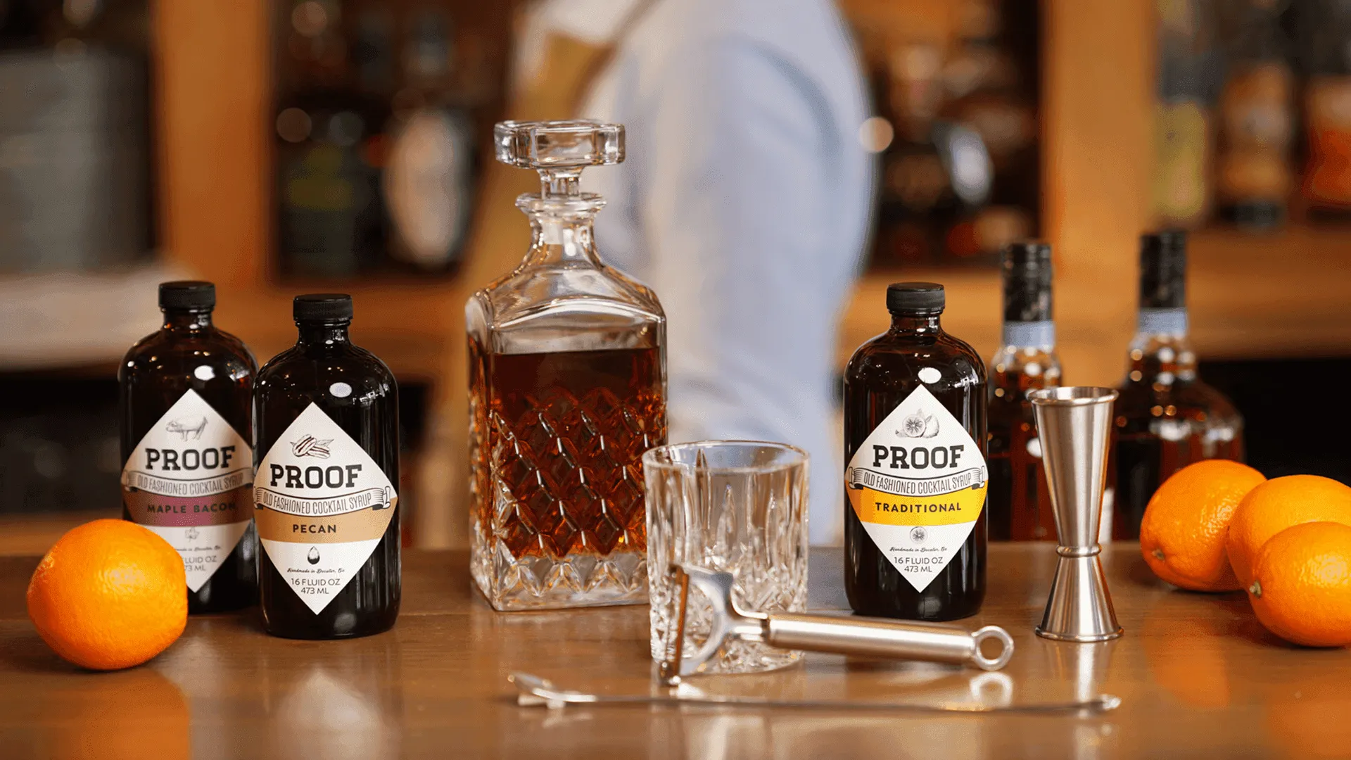 Bottles of Proof Cocktail syrup on a table with old fashion ingredients