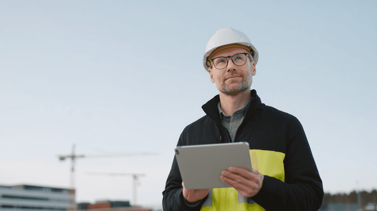 man holding tablet, wearing cap and glasses