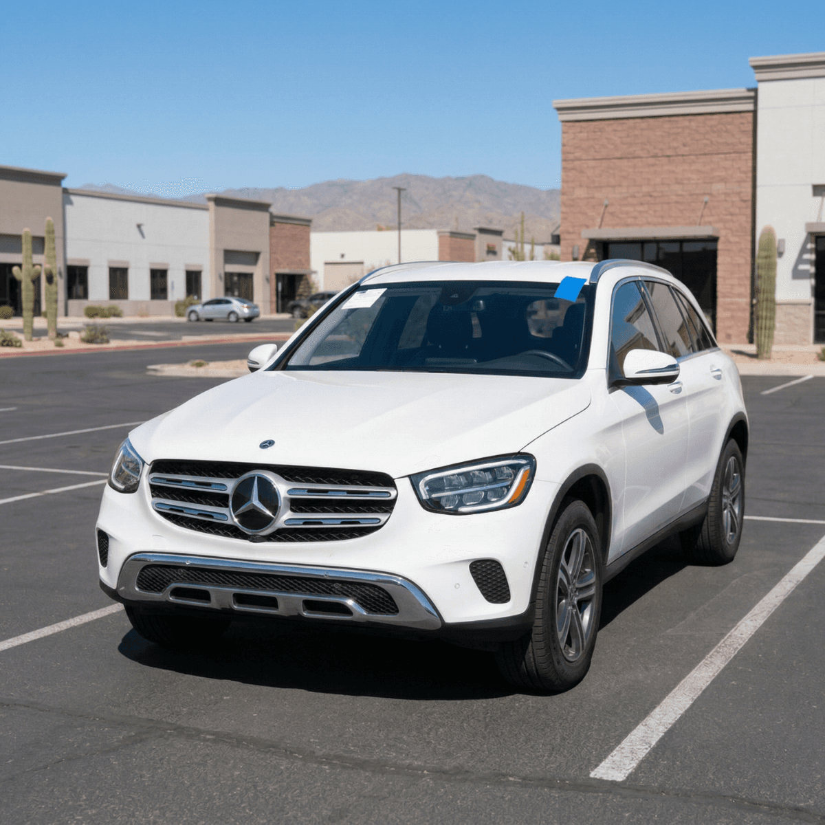 White Mercedes-Benz GLC SUV serviced with replacement auto glass at an Eloy commercial plaza