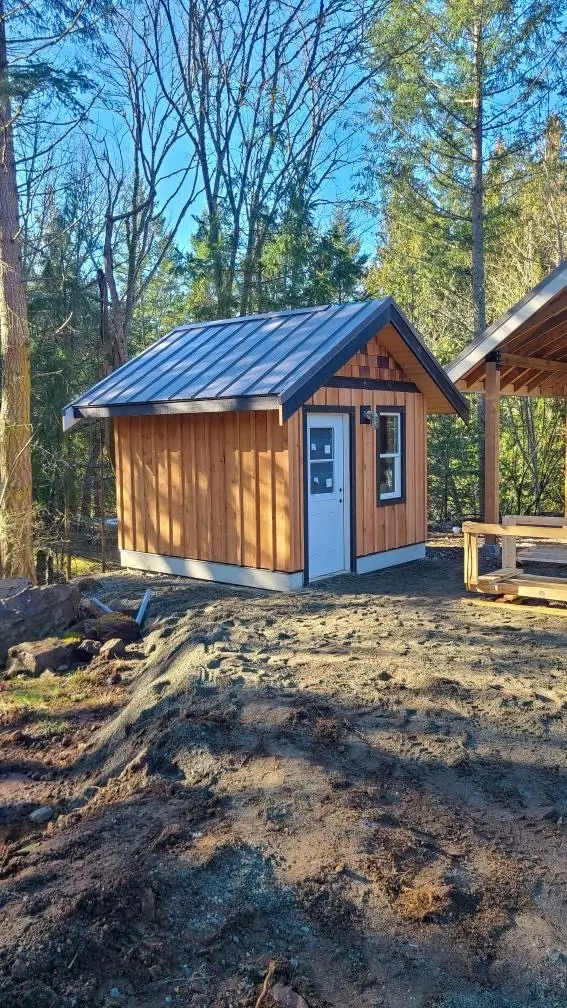 Small cedar tiny home with metal roof built in forest setting