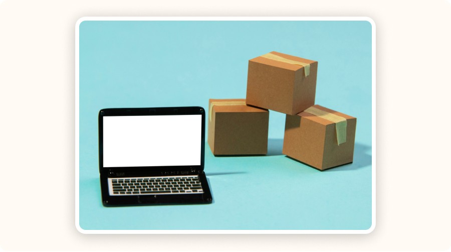 Ordinateur portable avec écran vide à côté de trois cartons empilés sur fond bleu