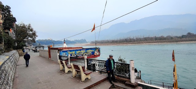 Aastha path along the Ganges river. A temple located on the banks and Uttarakhand mountains in the distance.