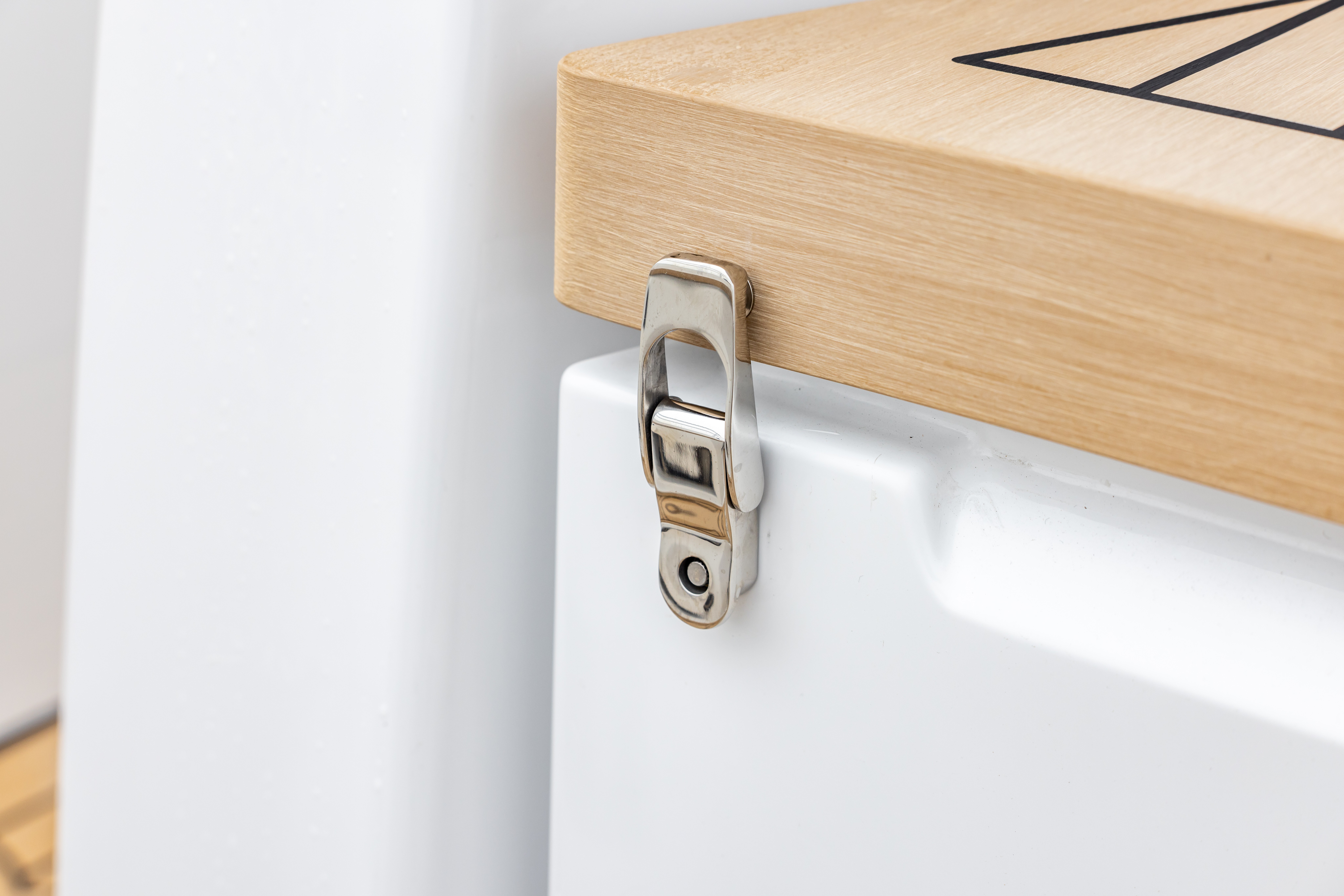 Close-up detail of an EcoDeck composite panel edge showing precision-machined light oak surface finish and integrated polished stainless steel hatch latch, demonstrating the quality of EcoDeck material compatibility with marine-grade deck hardware