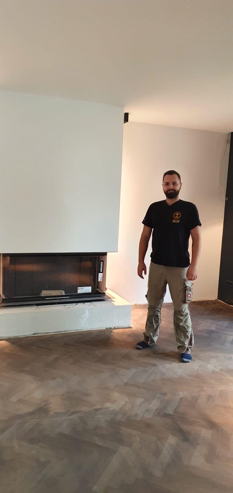 Mann steht auf Parkett neben Kamin