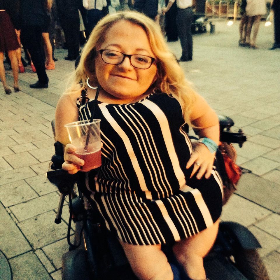 21 year old Gem in wheelchair with stripy dress on holding a drink outside