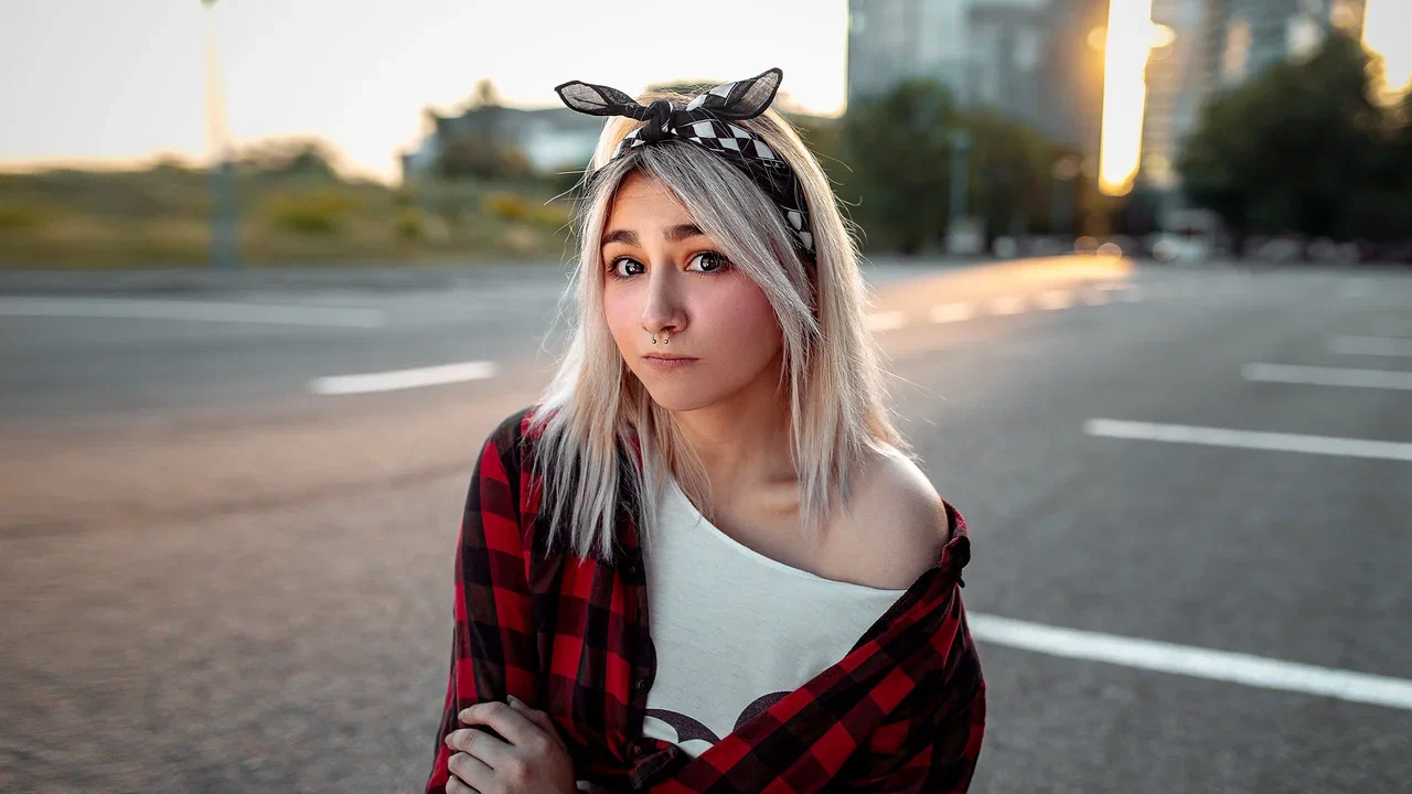 Woman applying facial oil drop to cheek from glass bottle