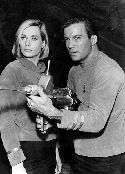 Star Trek image of Captain Kirk with a crew member beside him, he is holding an energy weapon in a firing position