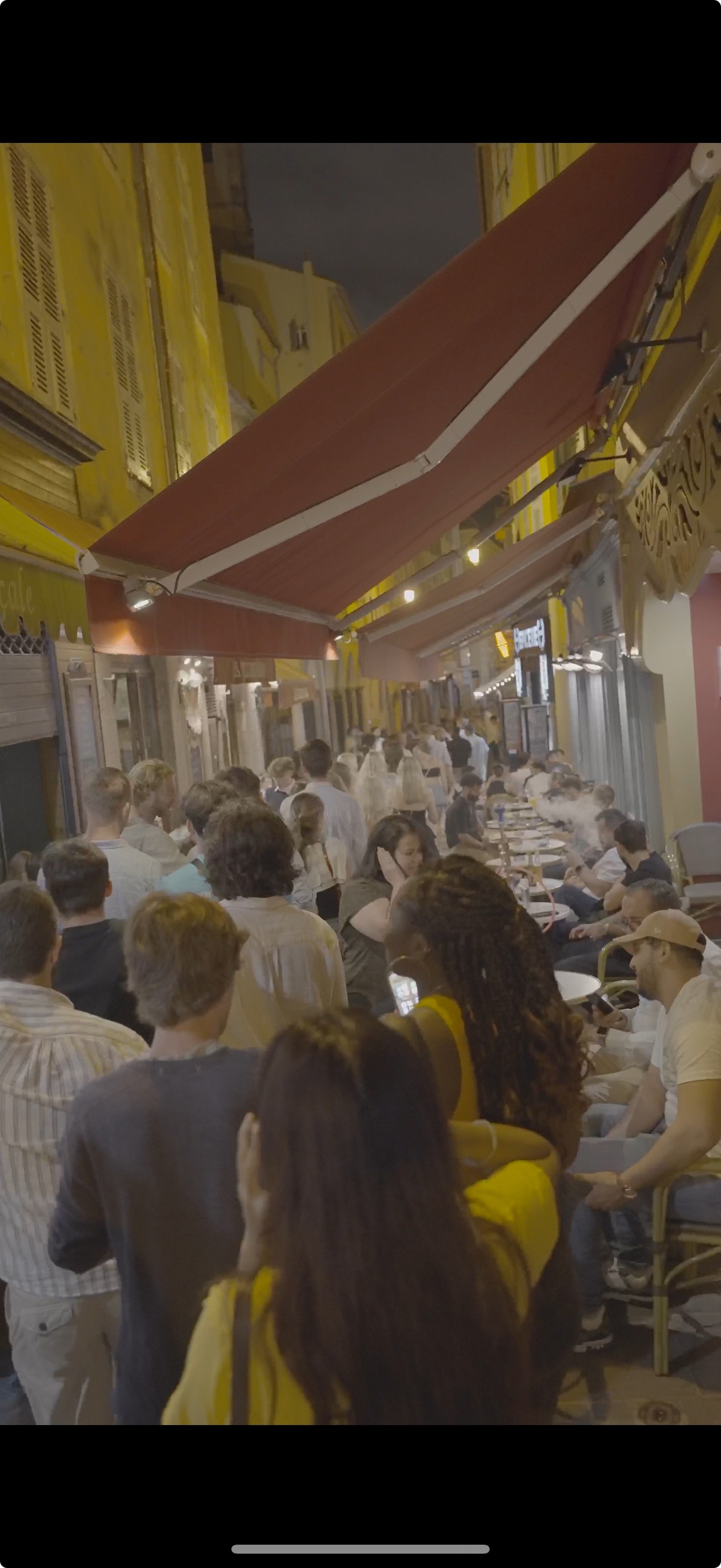 Two groups of travelers at night in Nice, one following a guided bar crawl and another choosing bars on their own in the Old Town.