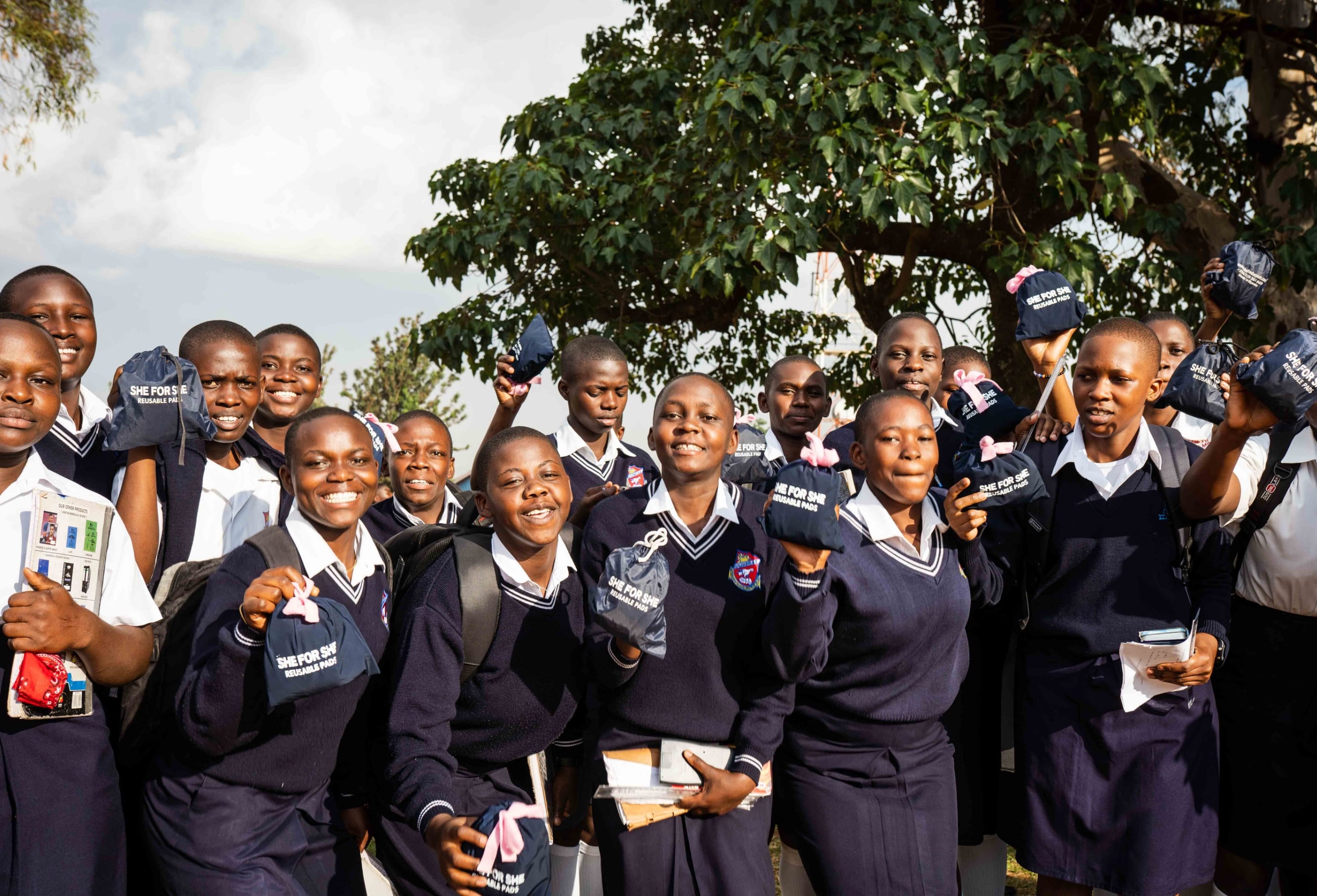 Group of girls smiling while holding SHE FOR SHE reusable menstrual pads.