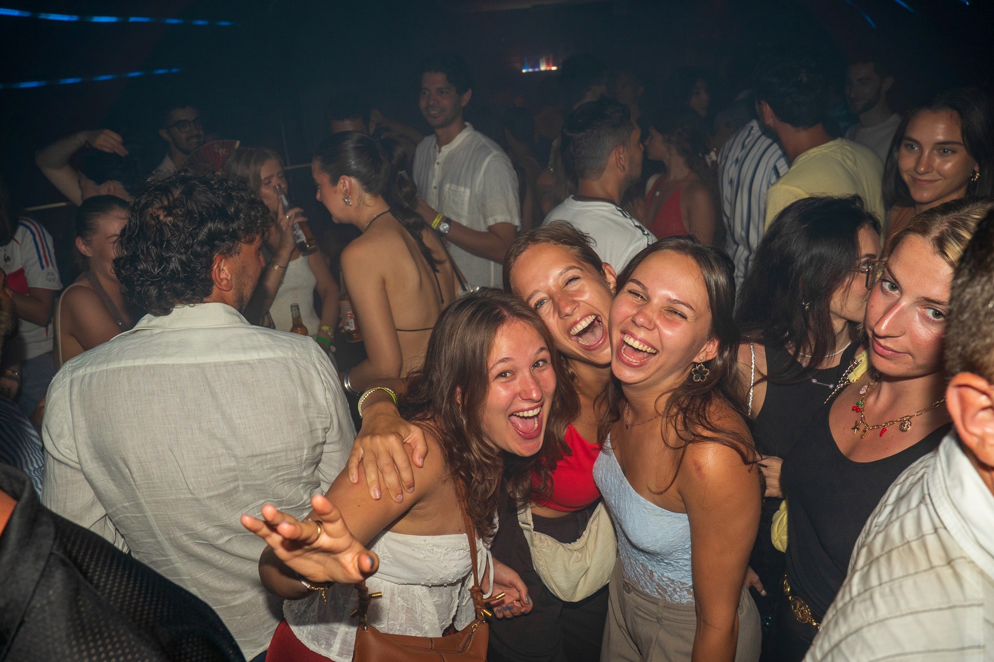 Group of young travelers laughing and celebrating together on a packed dance floor during a high energy bar crawl in Nice capturing intense party vibes and unforgettable nightlife moments in the French Riviera