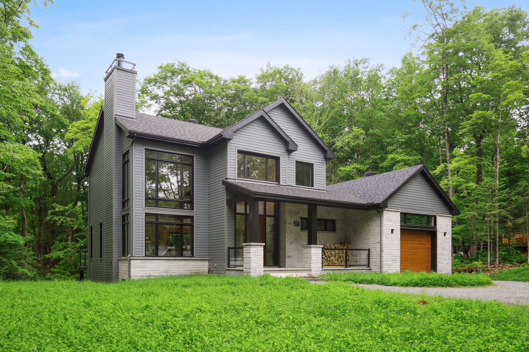 Vue de coin de la façade, grandes fenêtres et porche couvert.
