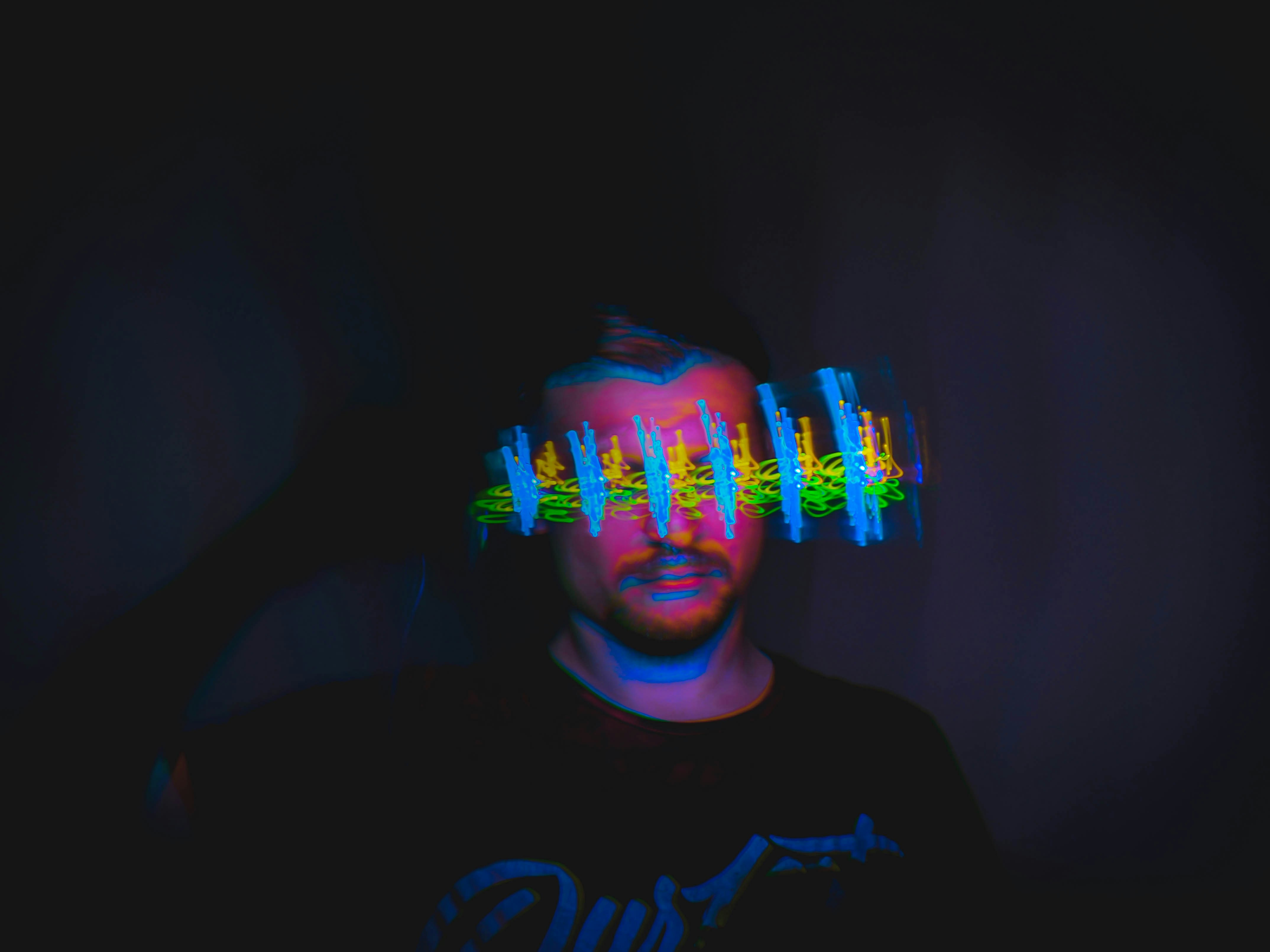 man in black crew neck shirt with blue and white light on his face