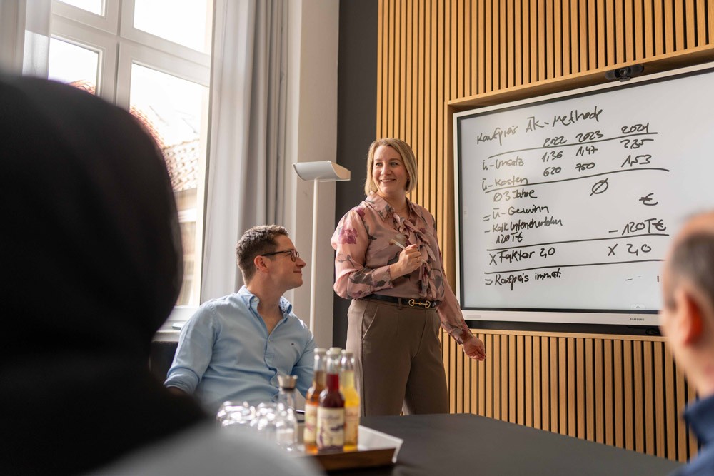 Präsentation bei SLB: Geschäftsführerin zeigt an einem Whiteboard ein Schaubild vor einer Gruppe von Zuhörenden.