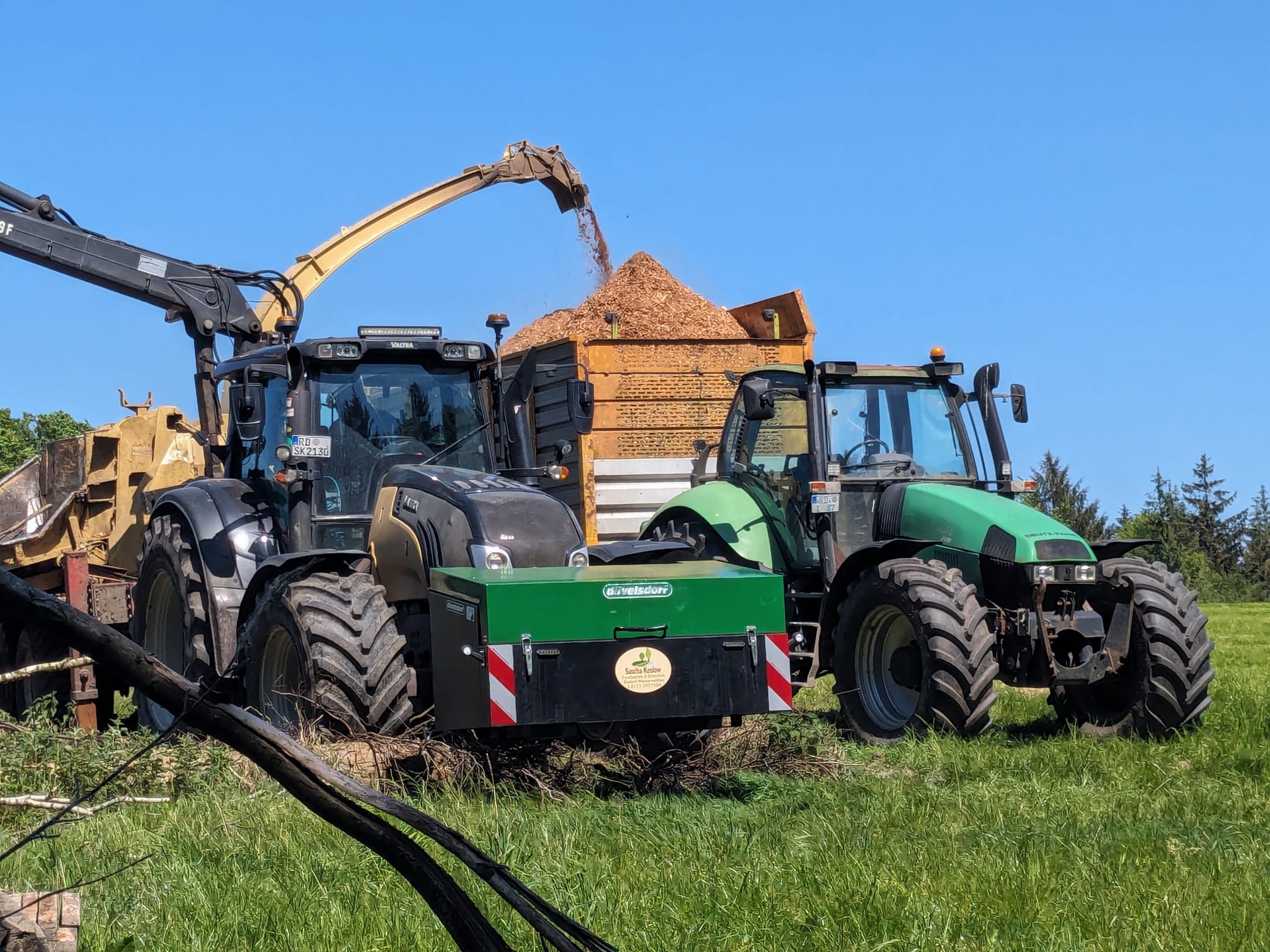 Traktor mit Schild auf einem großen Hackschnitzellager