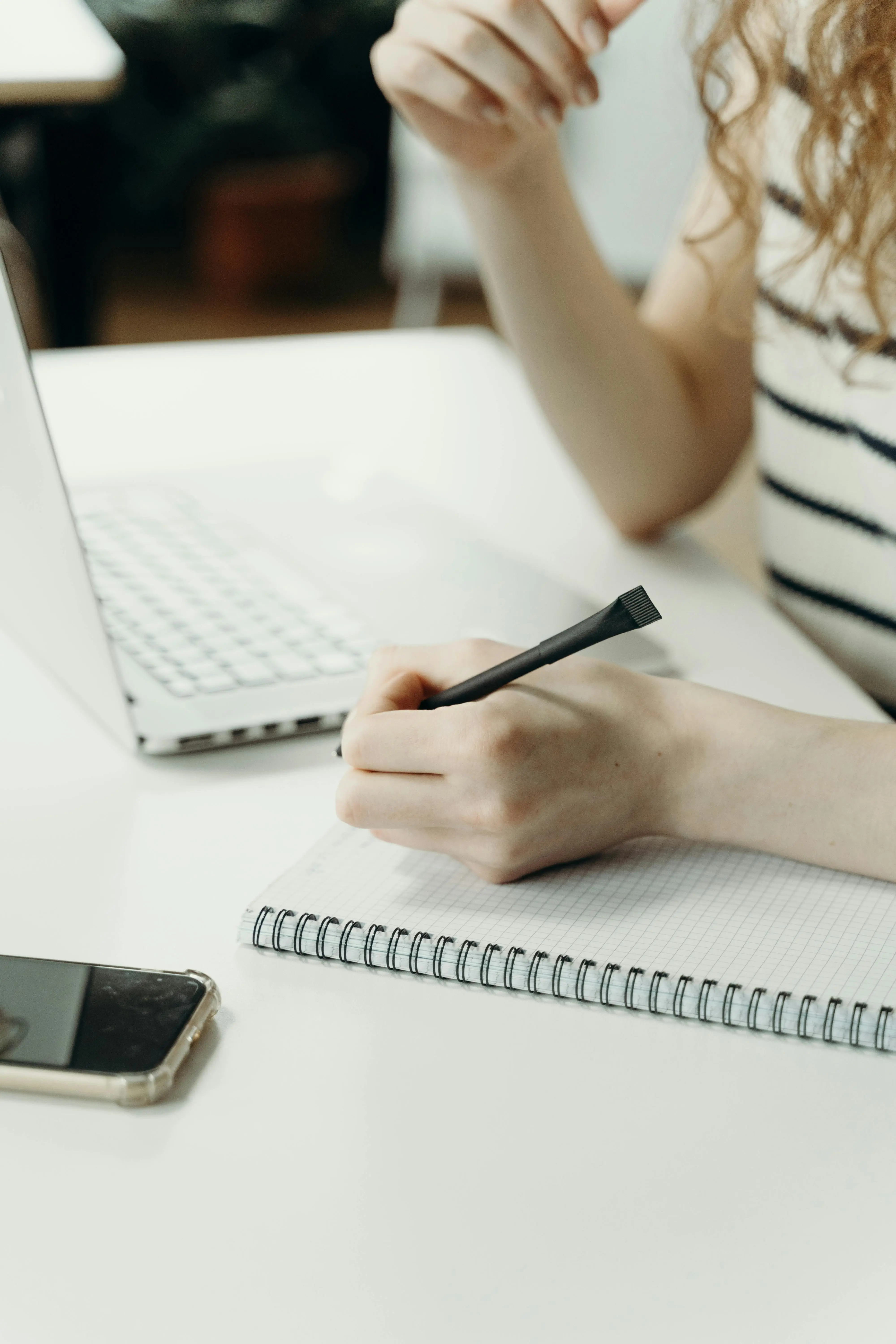 Close-up of a professional taking notes in a spiral notebook next to a laptop, reflecting on their career strategy and job search framework.