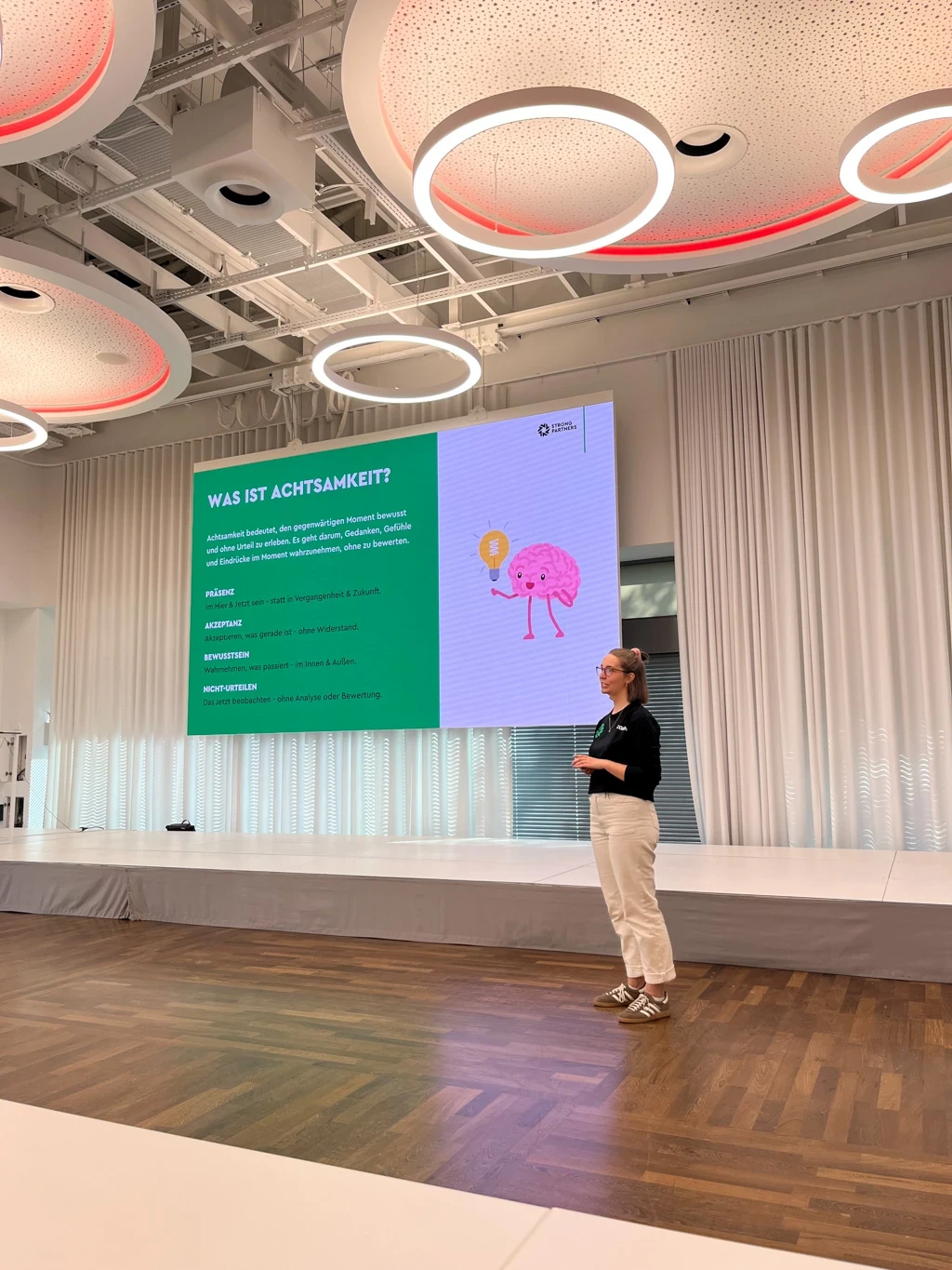 Eine junge Frau steht auf einer Bühne neben einer Präsentation