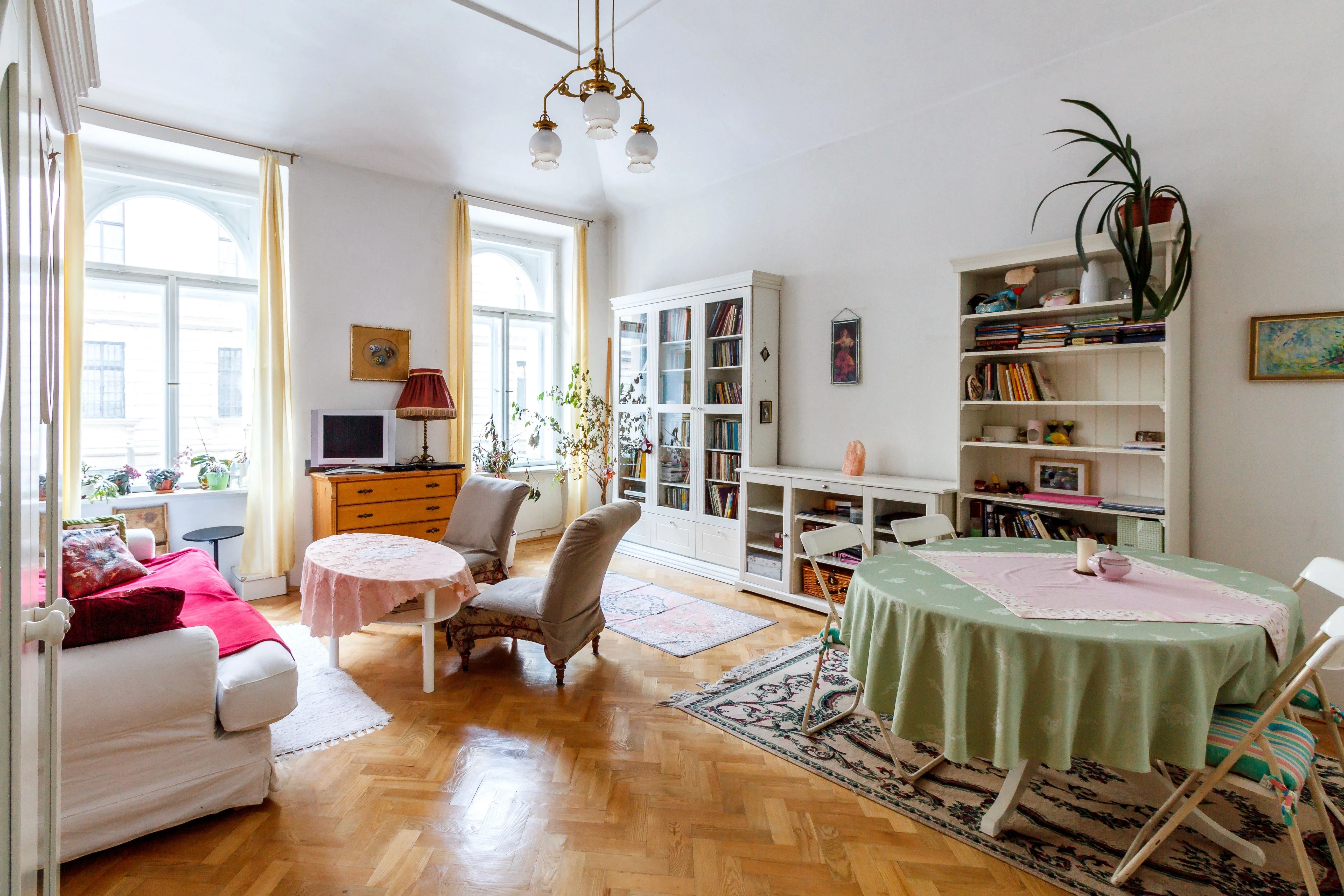Eclectic vintage living room filled with vibrant decor, potted plants, and natural sunlight.