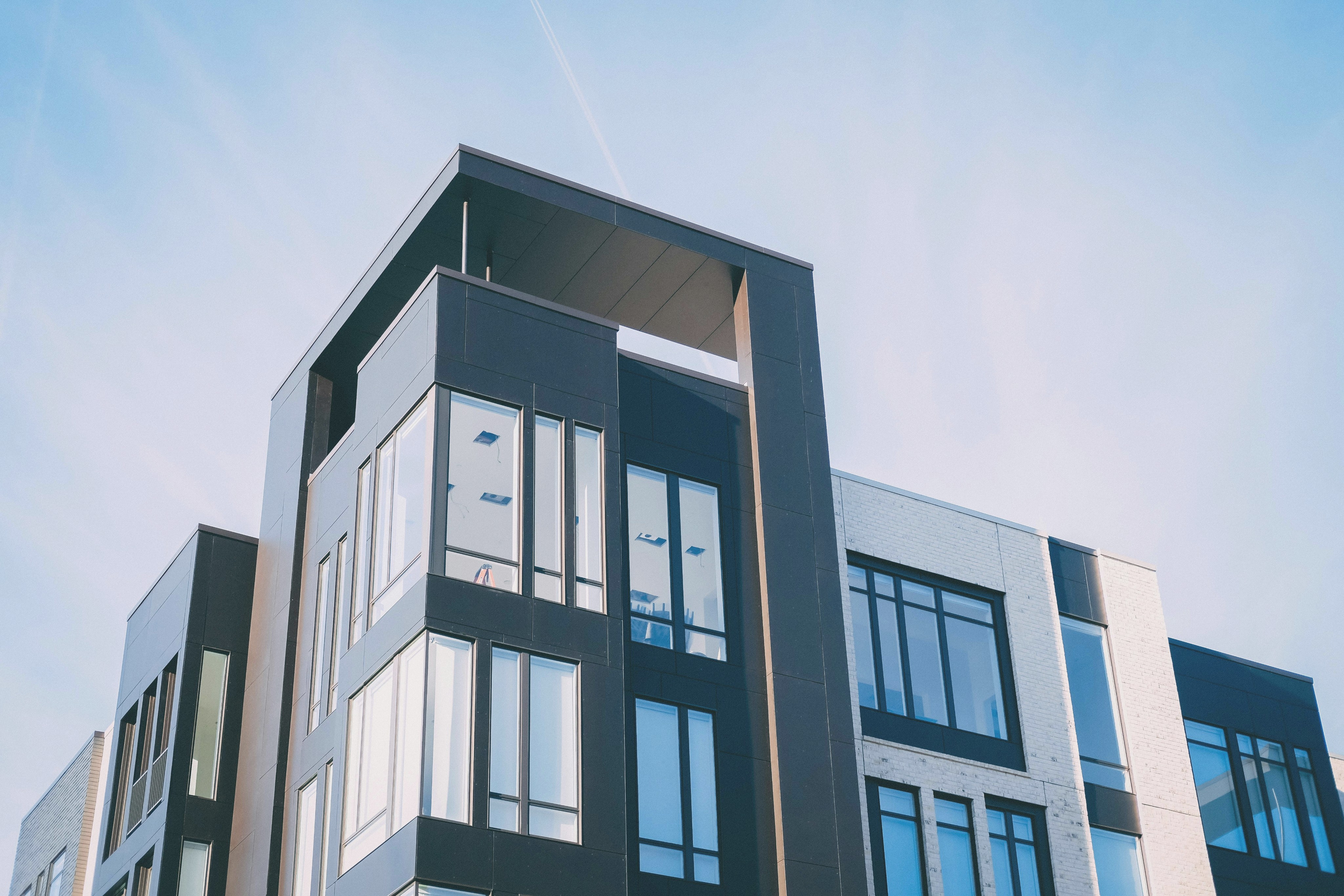 a modern apartment building exterior, shot from the ground looking up and including the sky