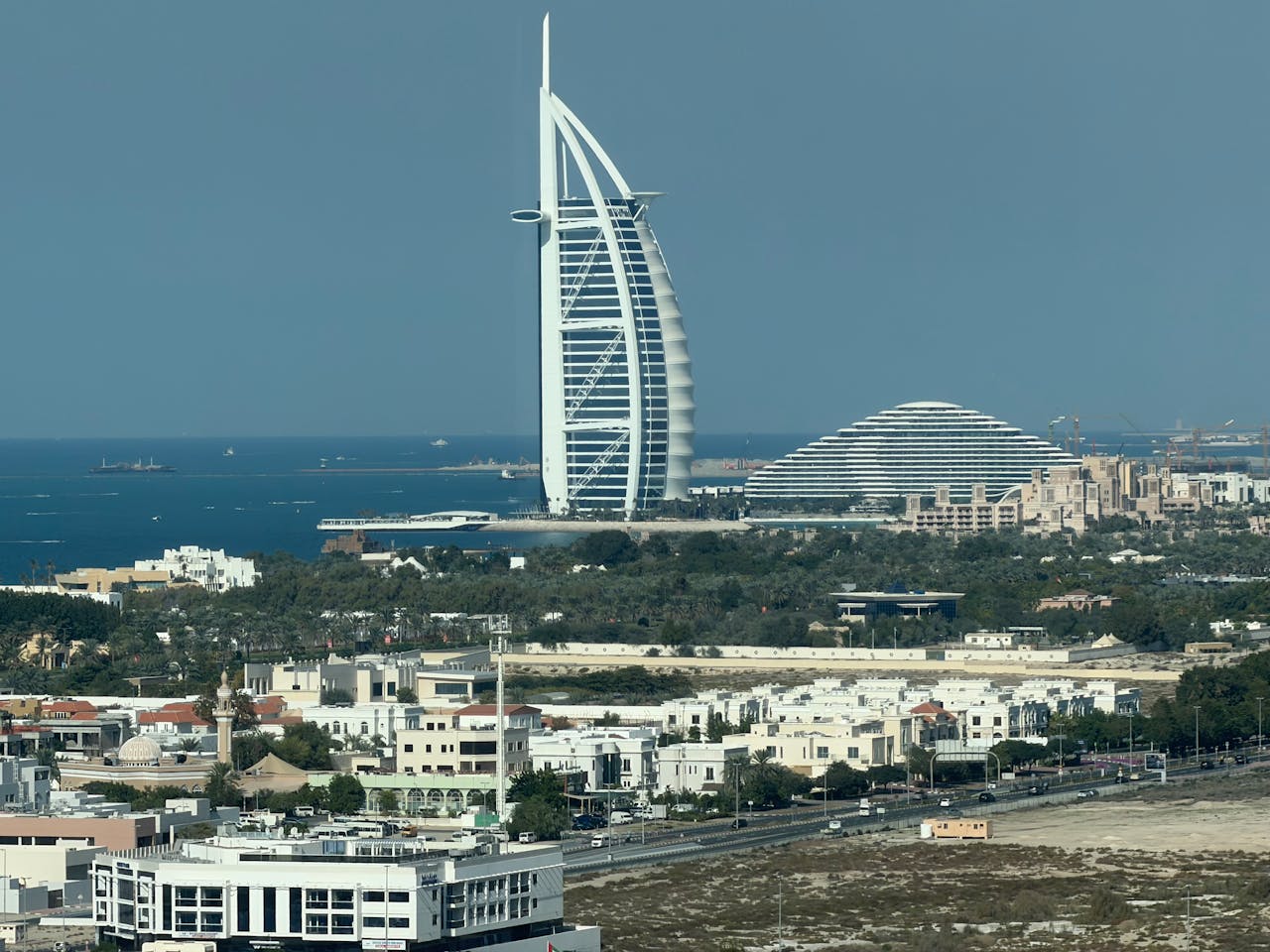 Rooftop view of the Burj al Arab with buildings surrounding it.