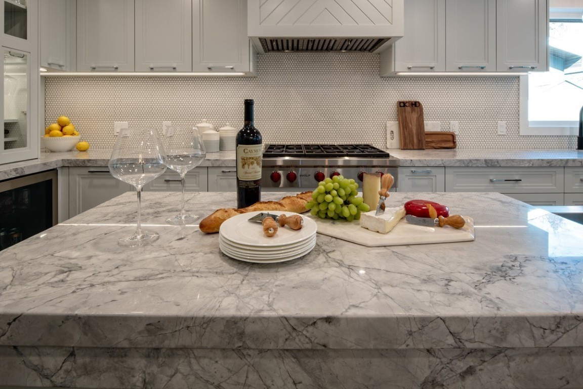 Image of Luxury kitchen interior with marble island, wine, and gourmet food, by KHD Homes design-build team.