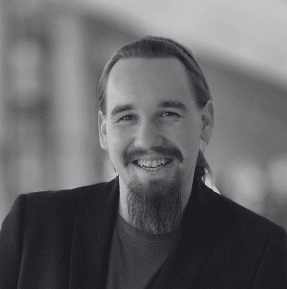 Portrait of a woman with long, smooth hair swept to the side, in a dark t-shirt, on a plain background.