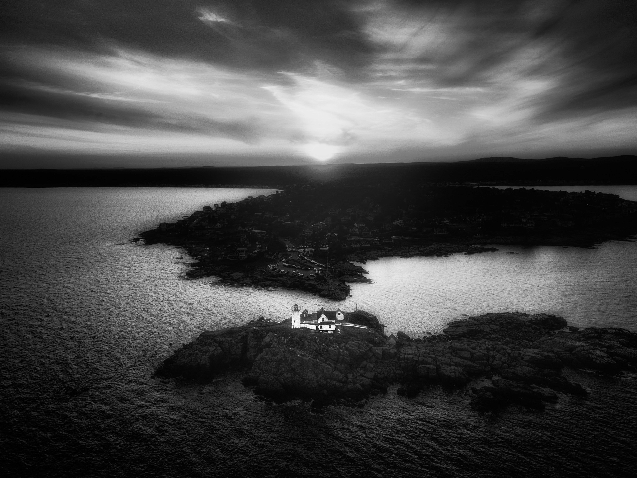 Two people holding each other looking at the sunset from the top of a mountain
