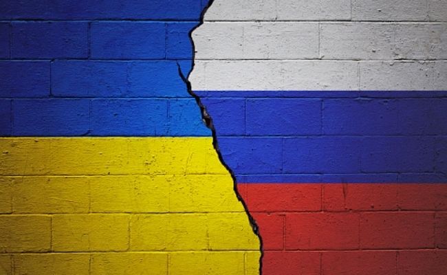 This is the image of  Ukraine and Russian flags painted on a brick wall separated by a crack in the middle. The left half contains the Ukrainian flag with blue on top and yellow on the bottom while the right contains the Russian flag with white blue and red colors from top to bottom. 