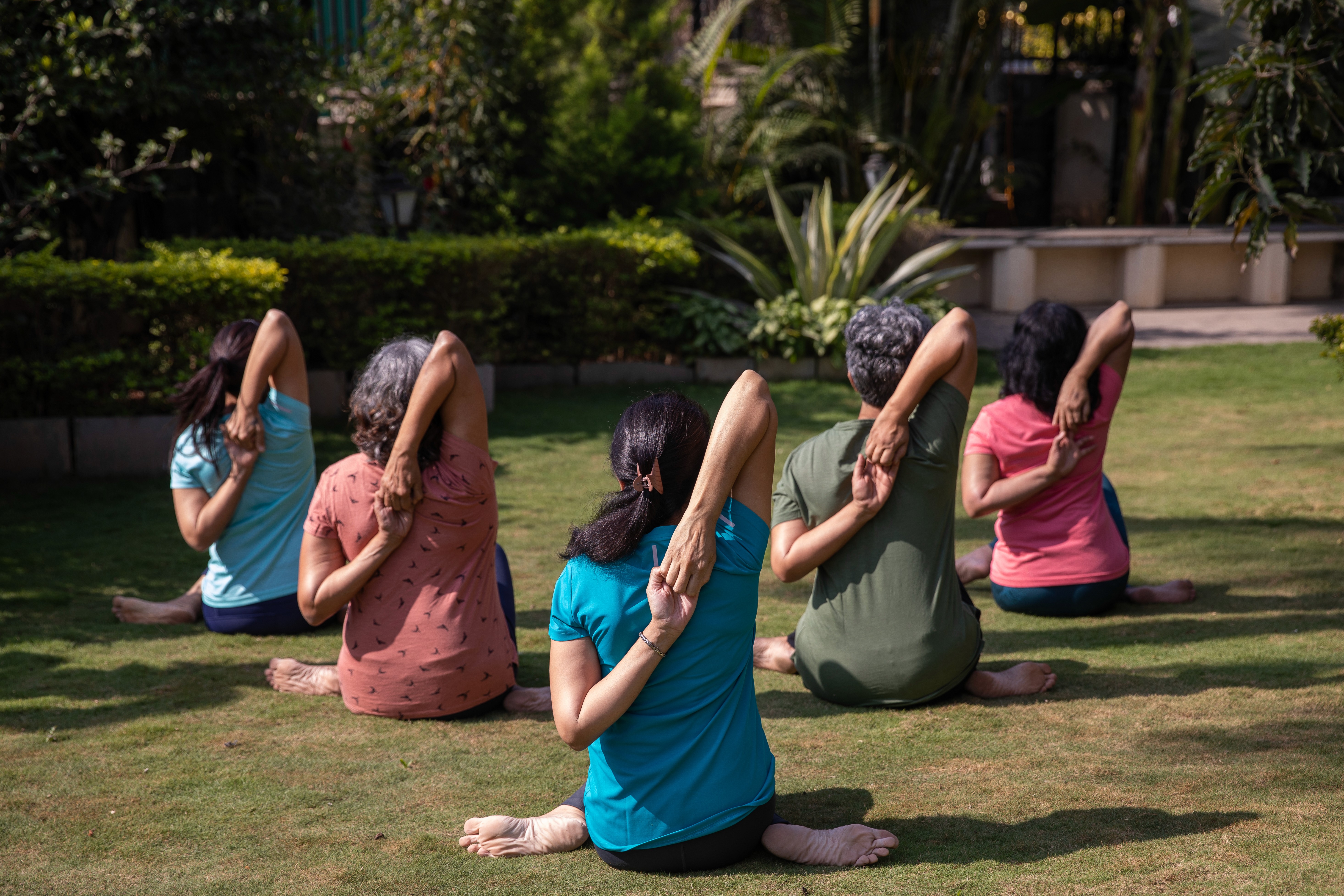 Members of TYC, practicing a seated yoga stretch outdoors.