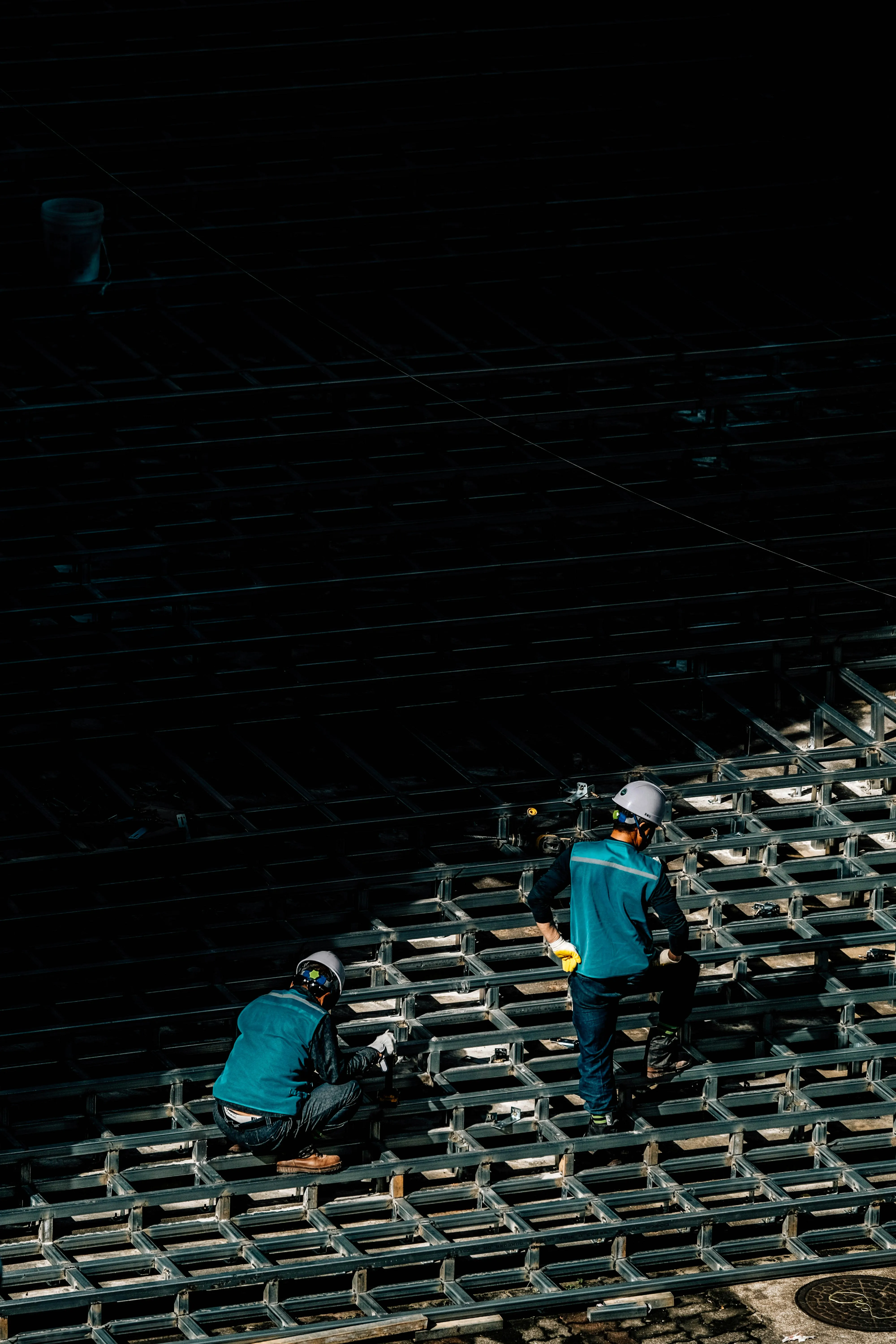 Two people in blue shirts are walking on empty seats in a dimly lit auditorium.