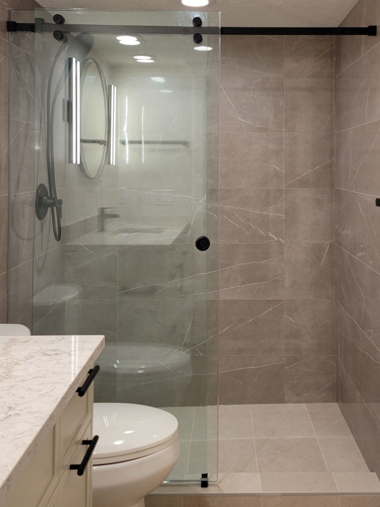 Image of Modern primary ensuite bathroom with glass shower door and marble tiles by KHD Homes design-build.