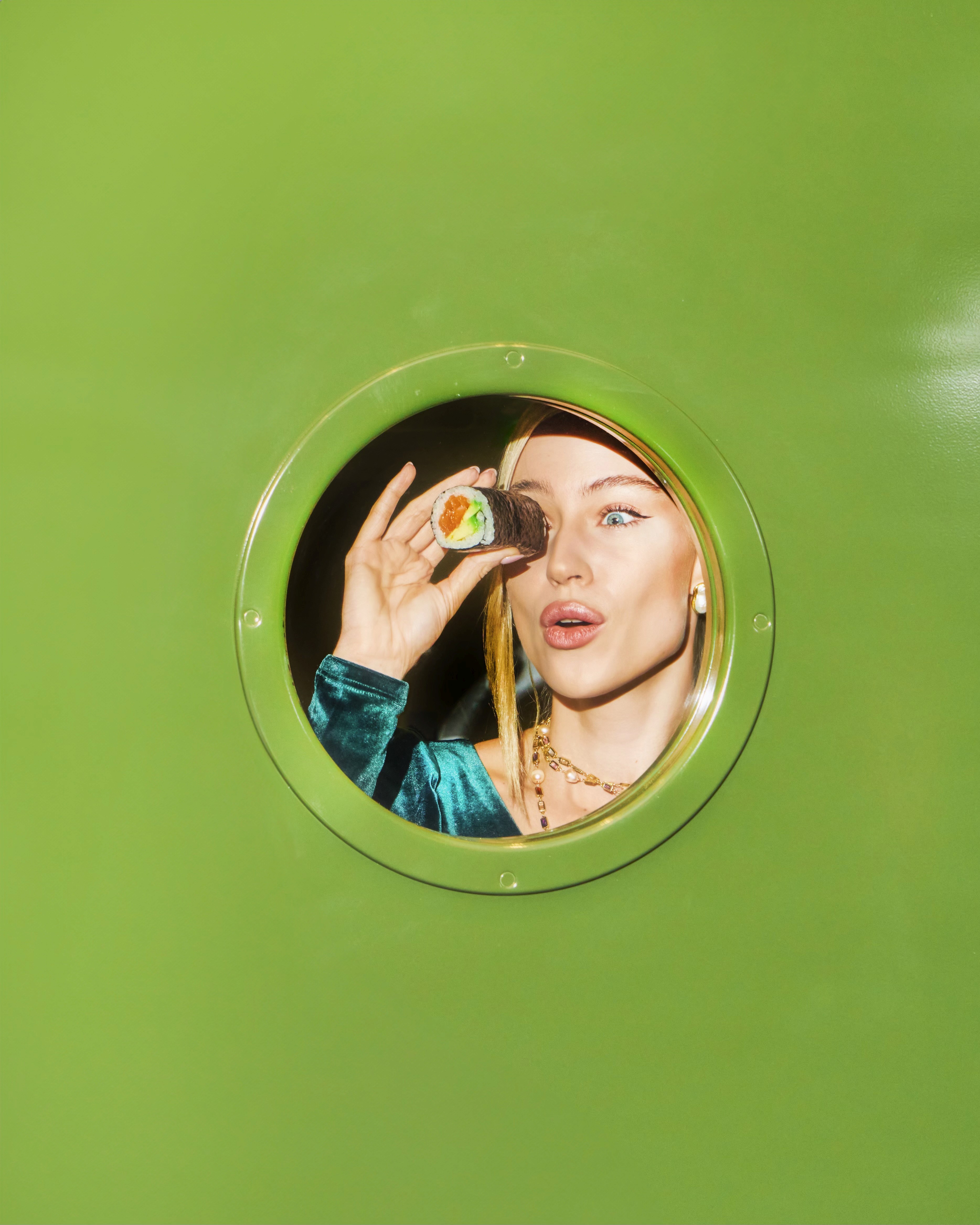 Portrait through a round mirror against a green wall