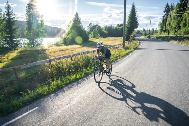 Cyclist riding along a quiet road through green countryside in soft daylight