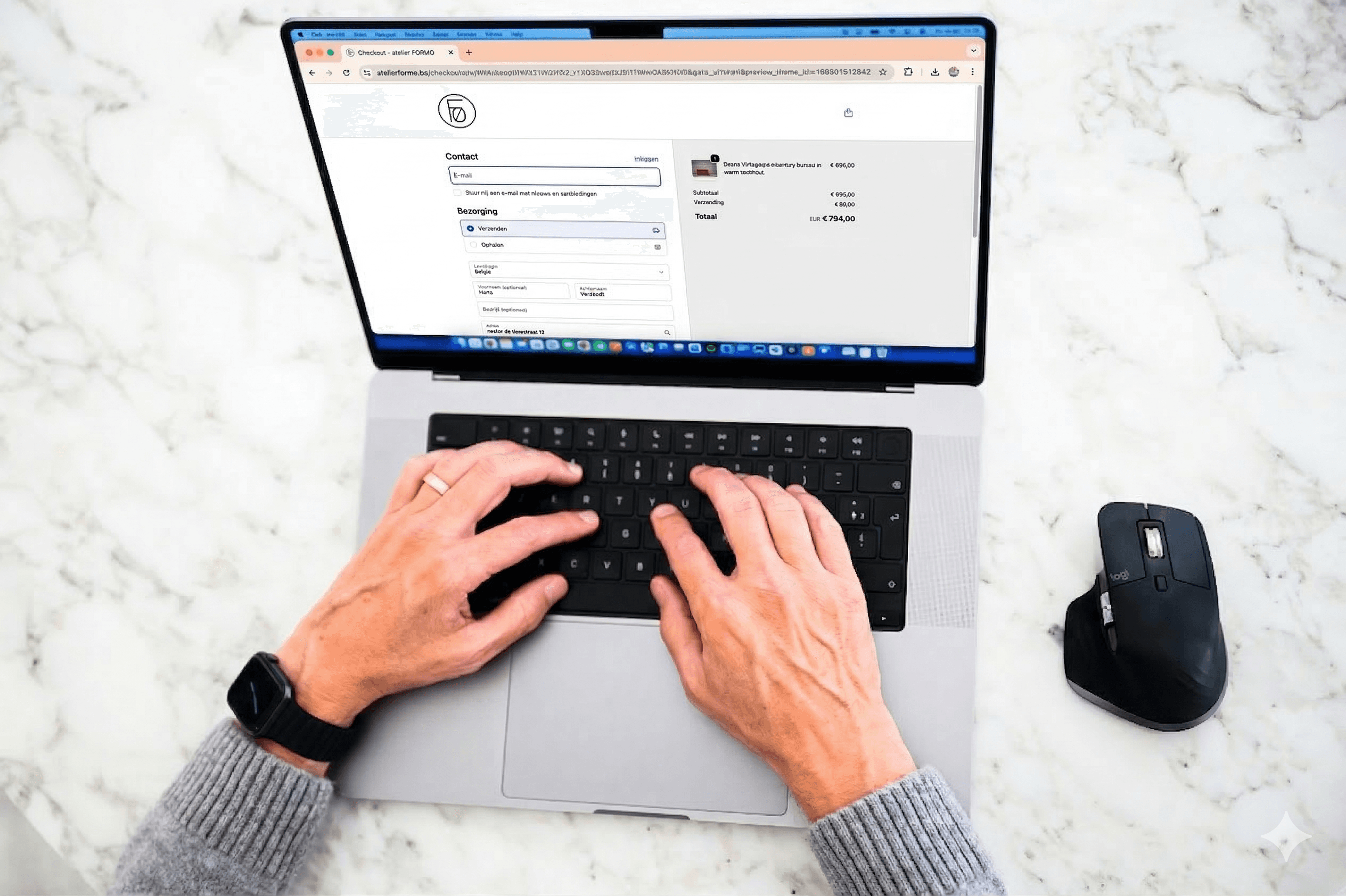 Bovenaanzicht van de 2 handen van Hans op het klavier van de laptop